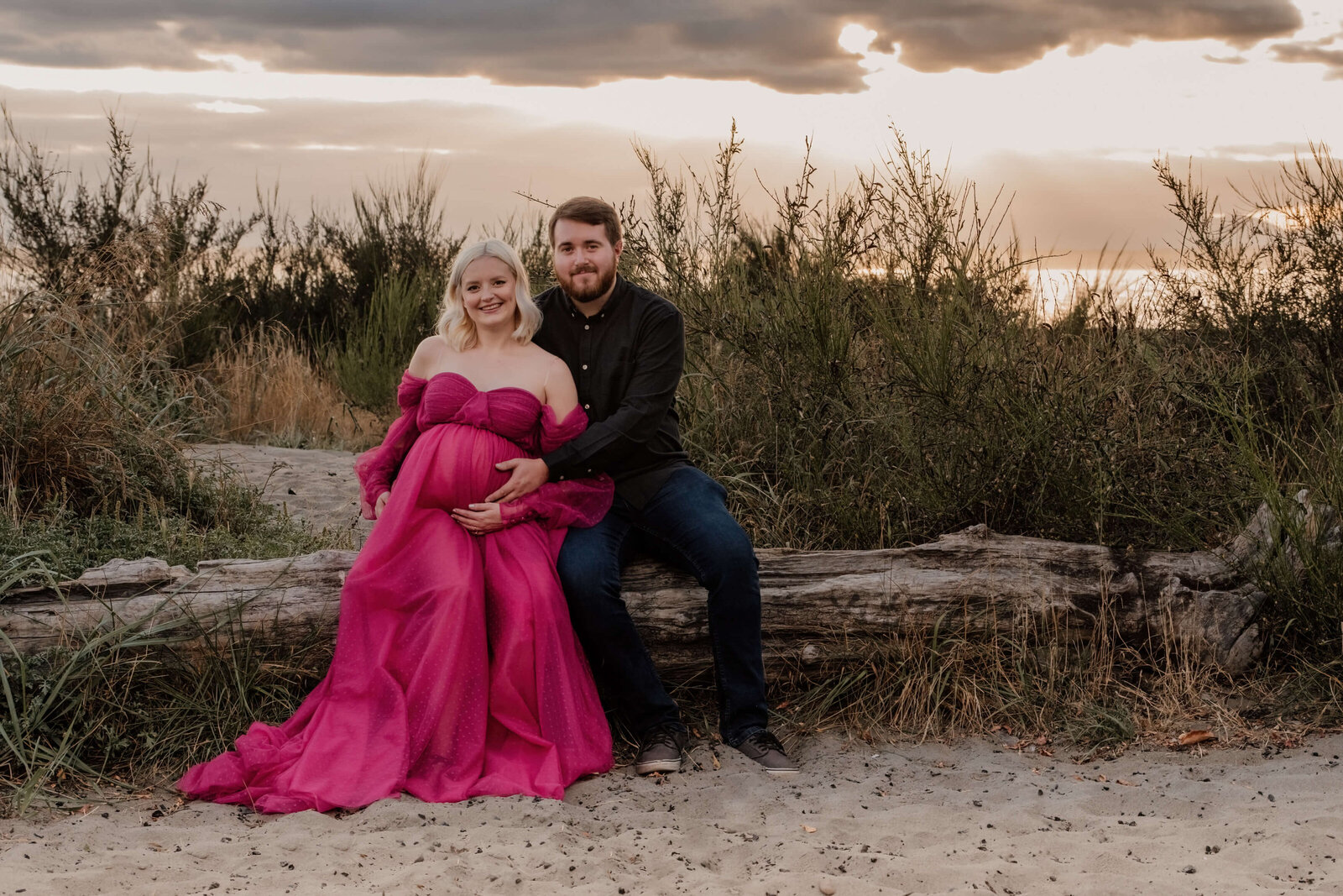 Couple sitting together on a log at the beach.