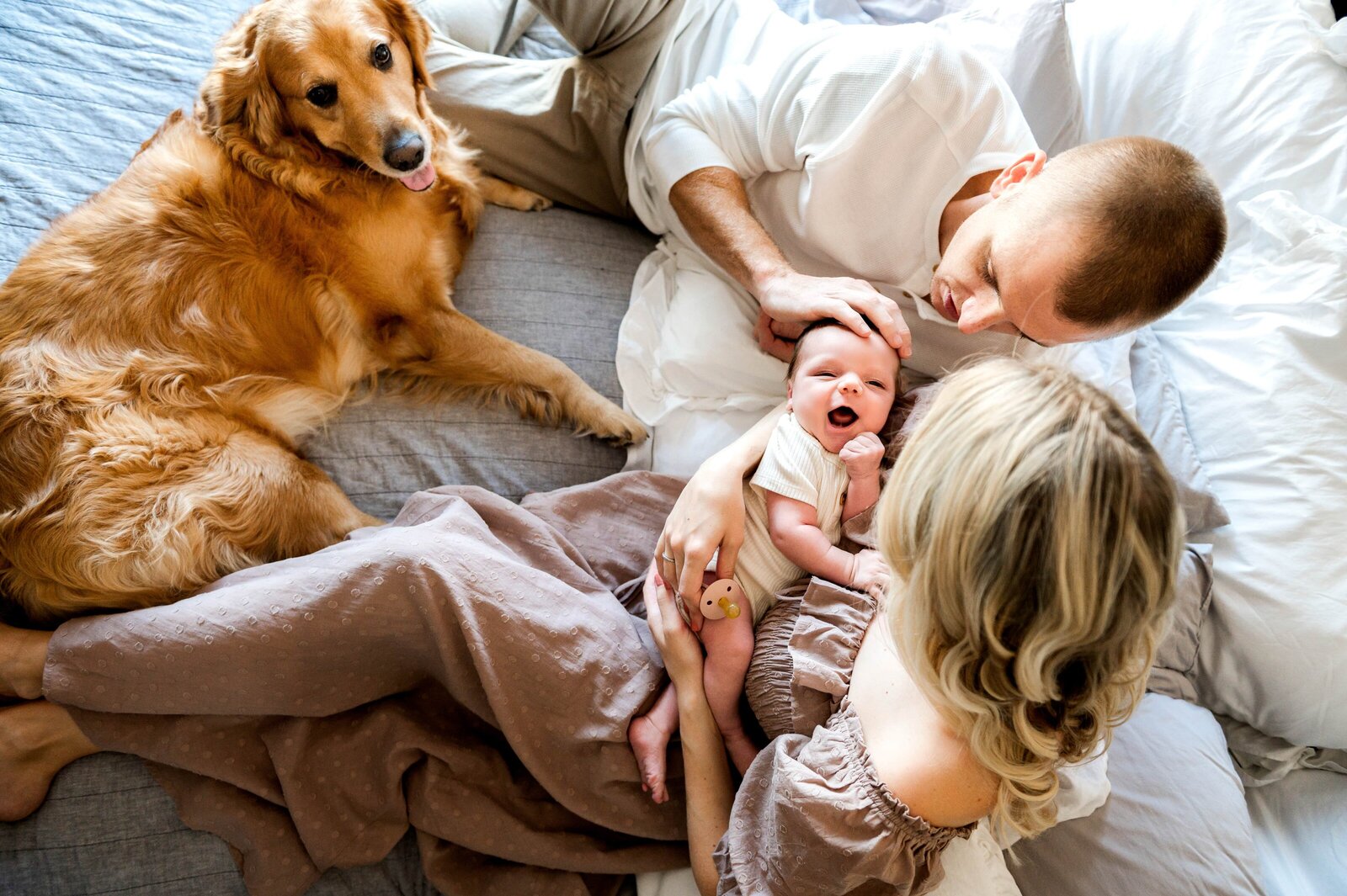 family on a bed holding a newborn boy during a baltimore newborn photoshoot
