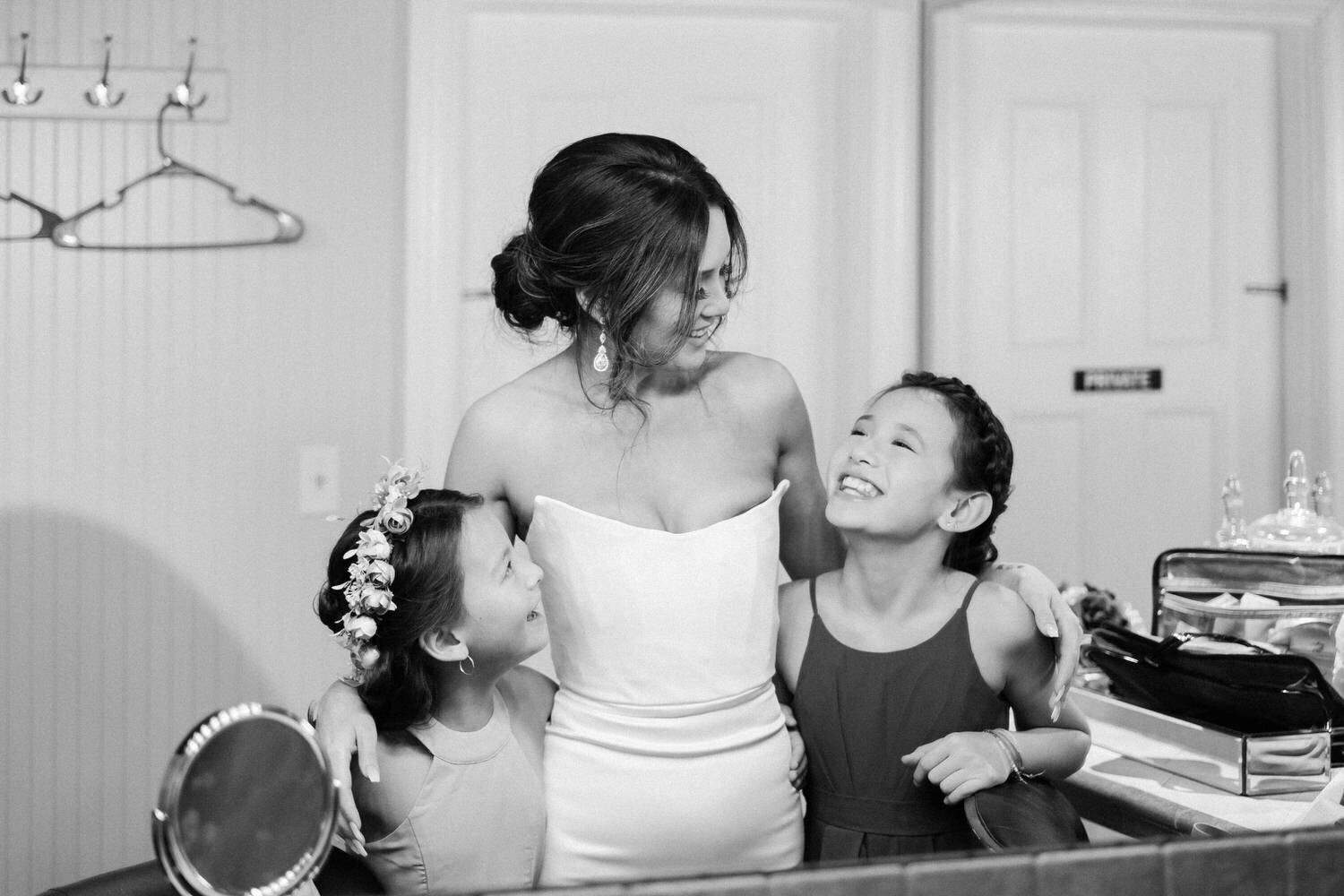 Bride hugs her daughters.