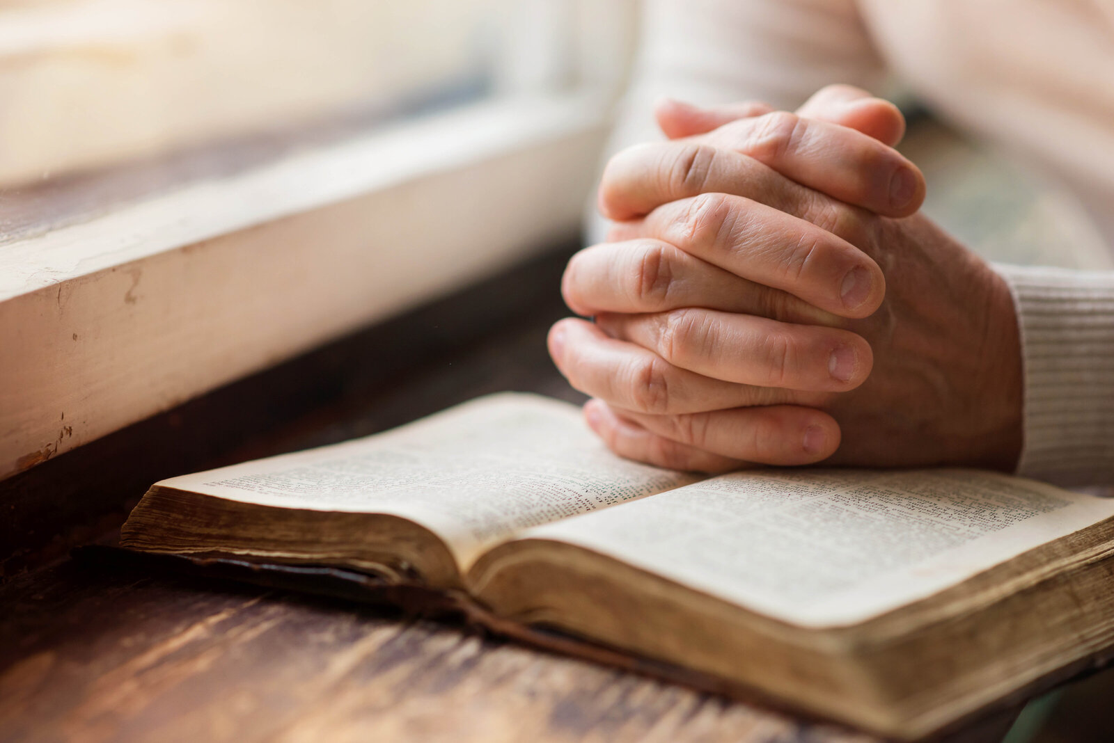 unrecognizable-woman-holding-a-bible-in-her-hands-and-praying-SBI-305129029
