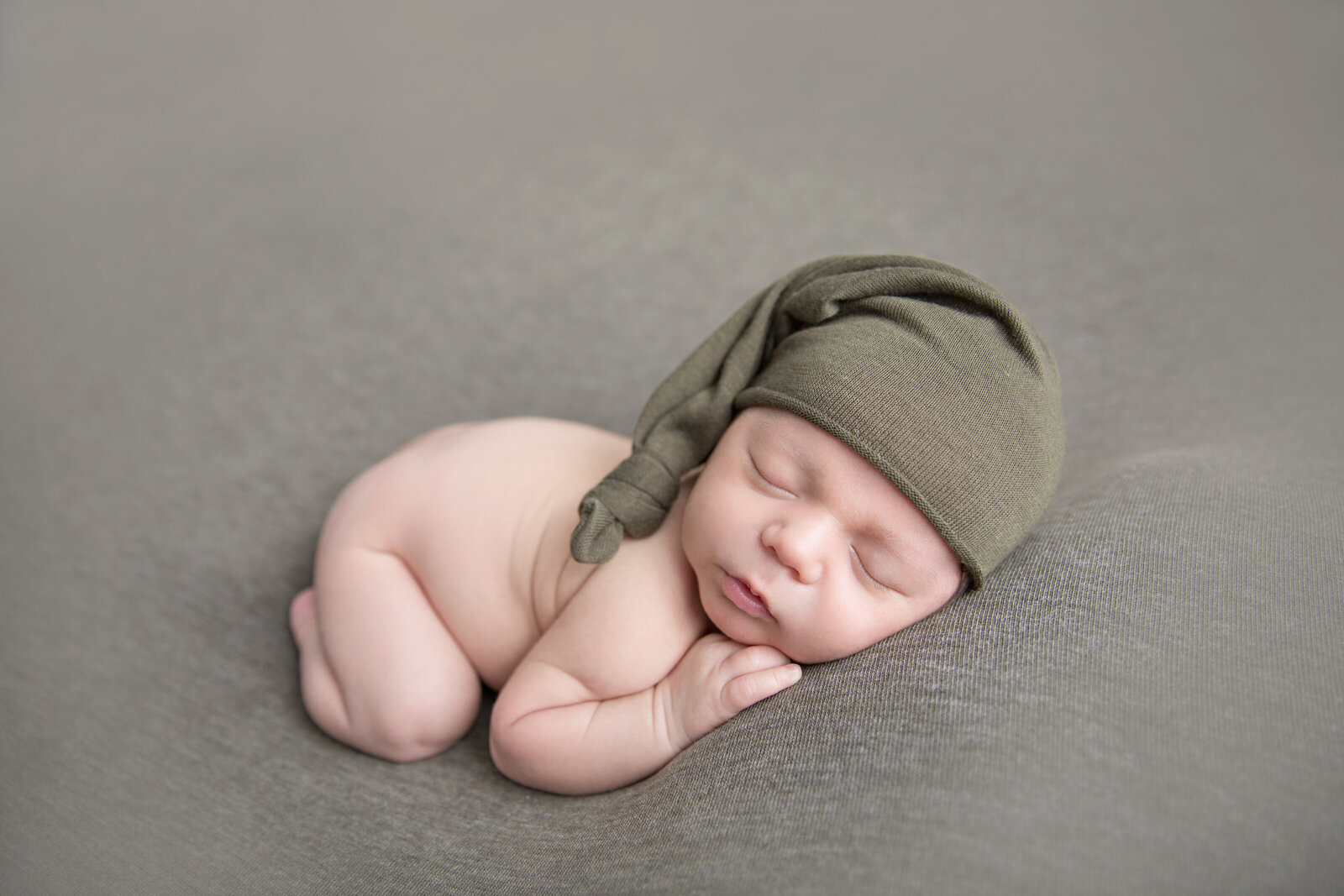 sleeping newborn baby in moss green hat