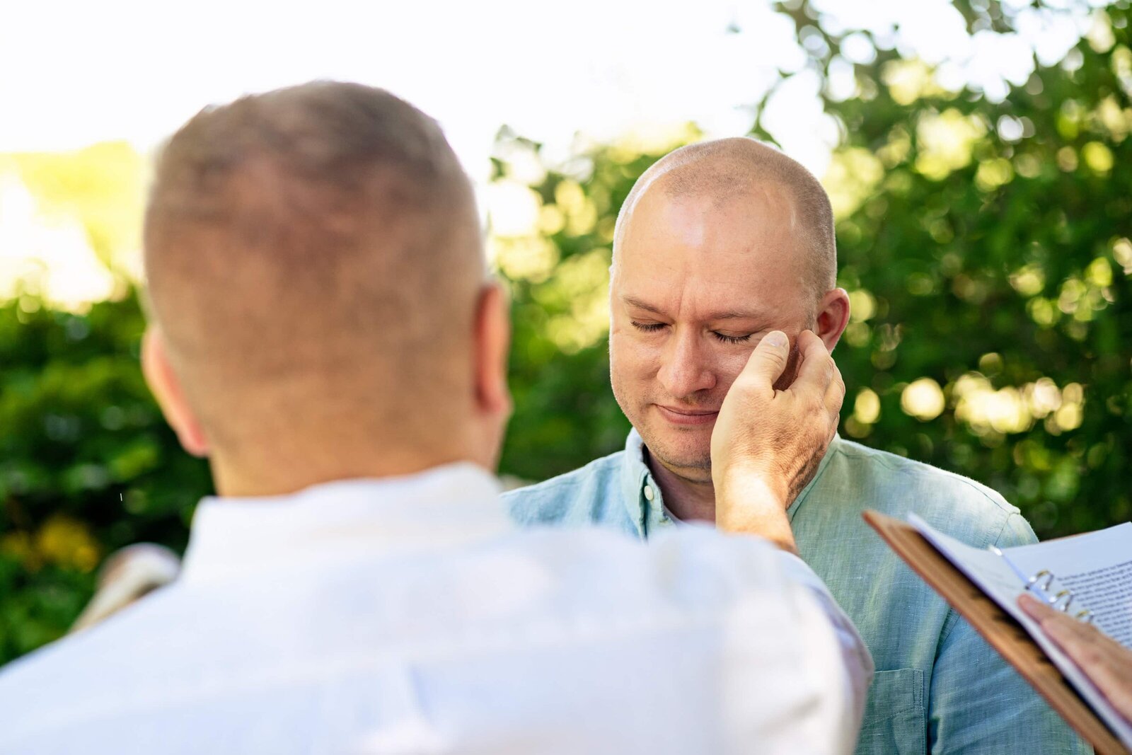 man wipes tears from another man's face as the two exchange vows during this same-sex wedding in Raleigh, North Carolina