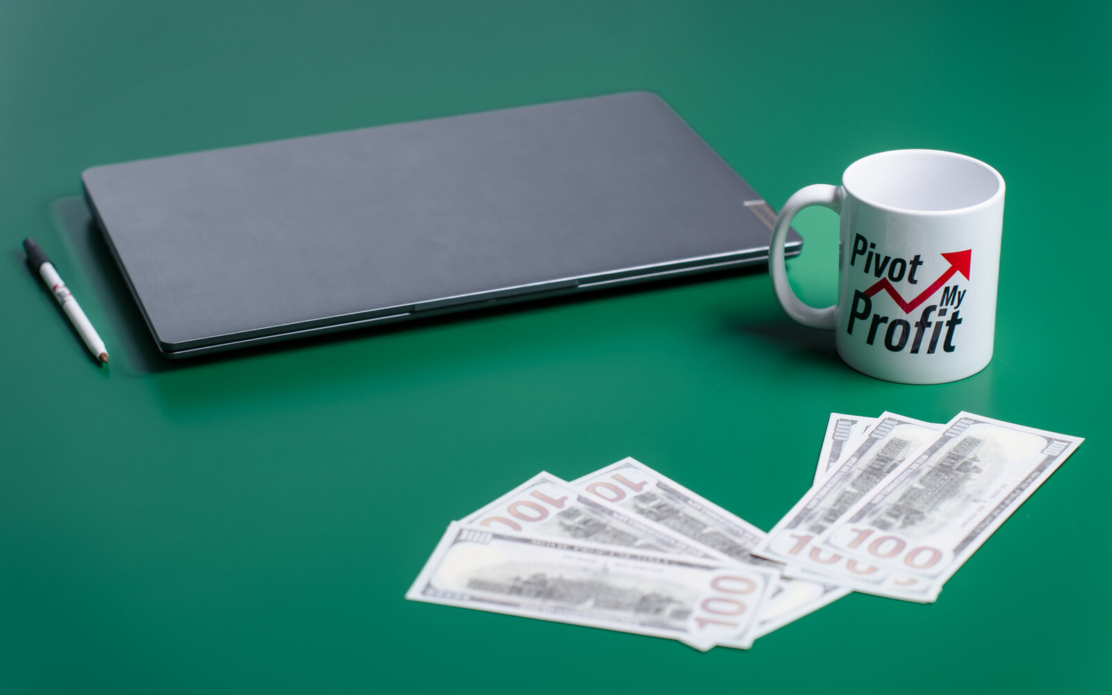 flat-lay photo of laptop, fake money and brand coffee mug