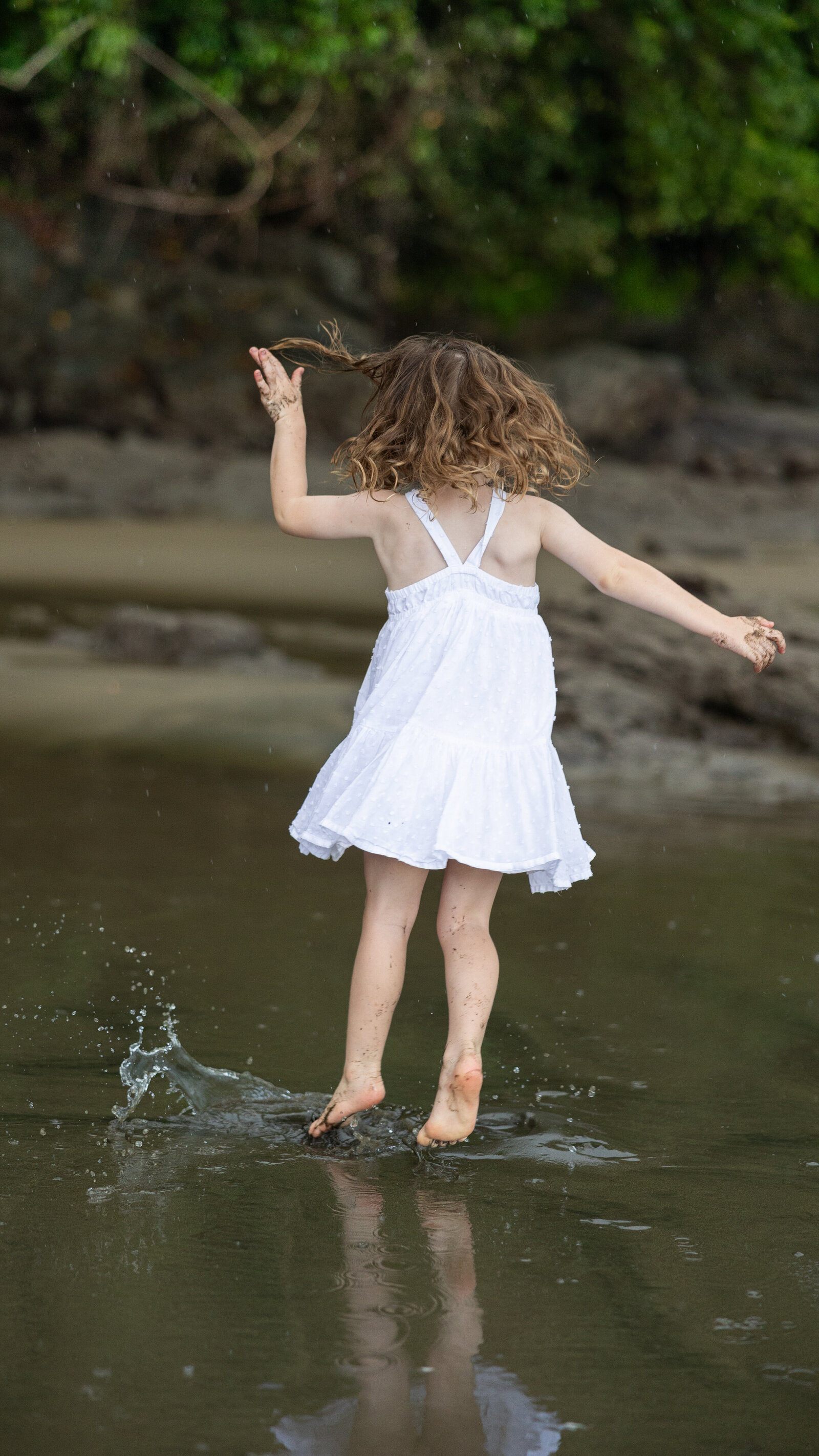 child jumping in puddles with a dress