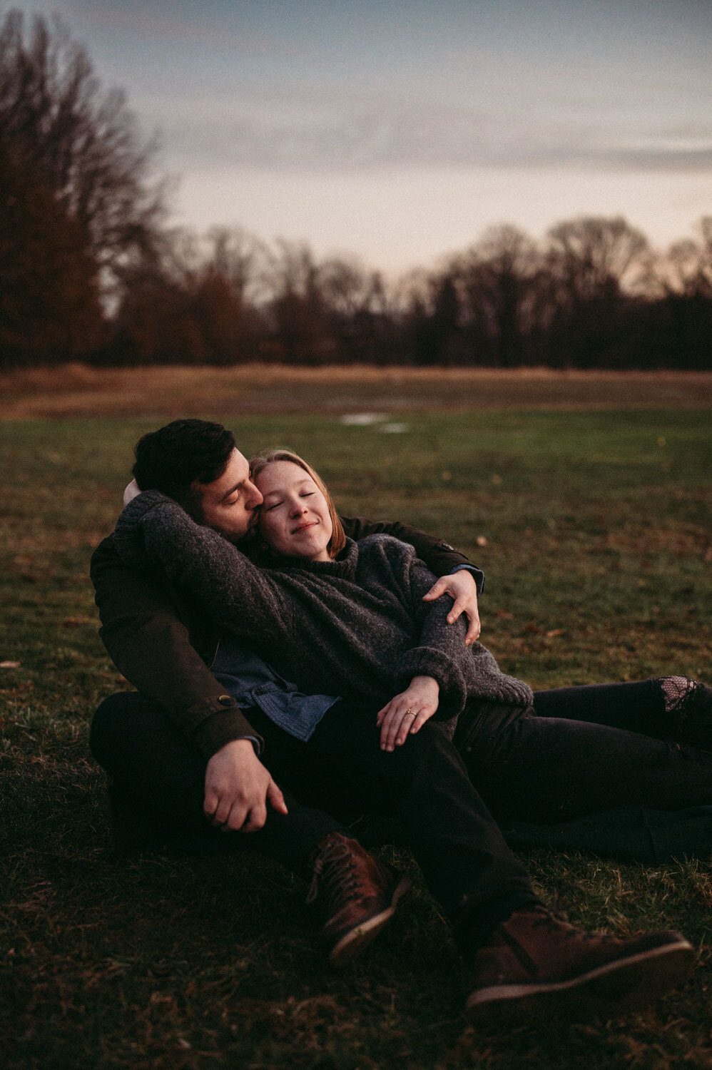 Couple snuggles together at golden hour in winter