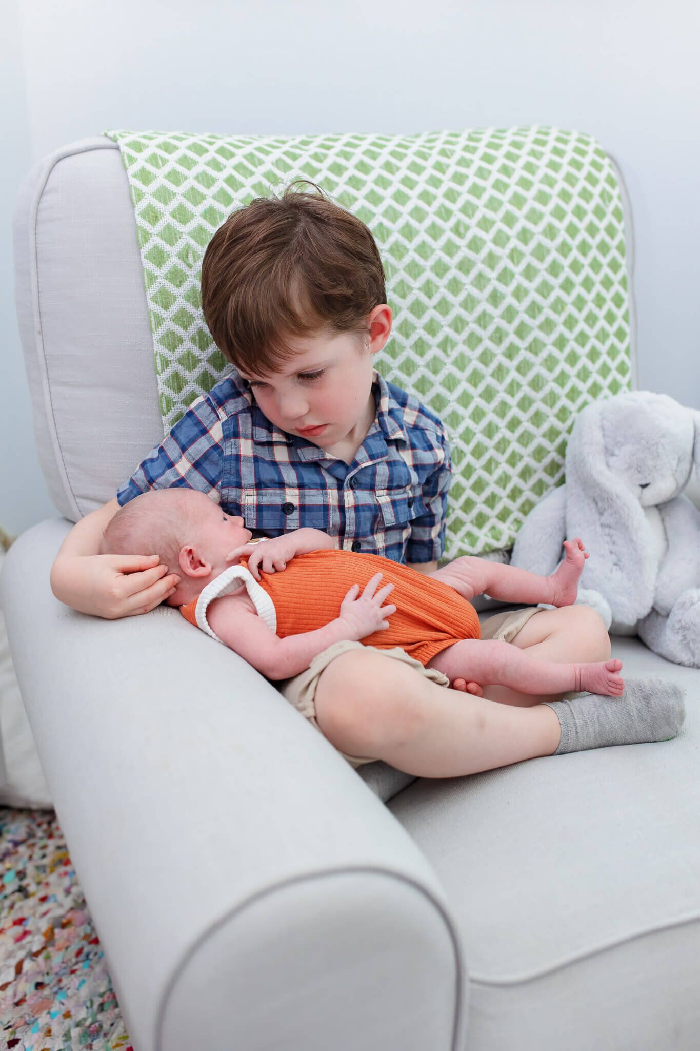 A little boy holding his newborn baby brother.