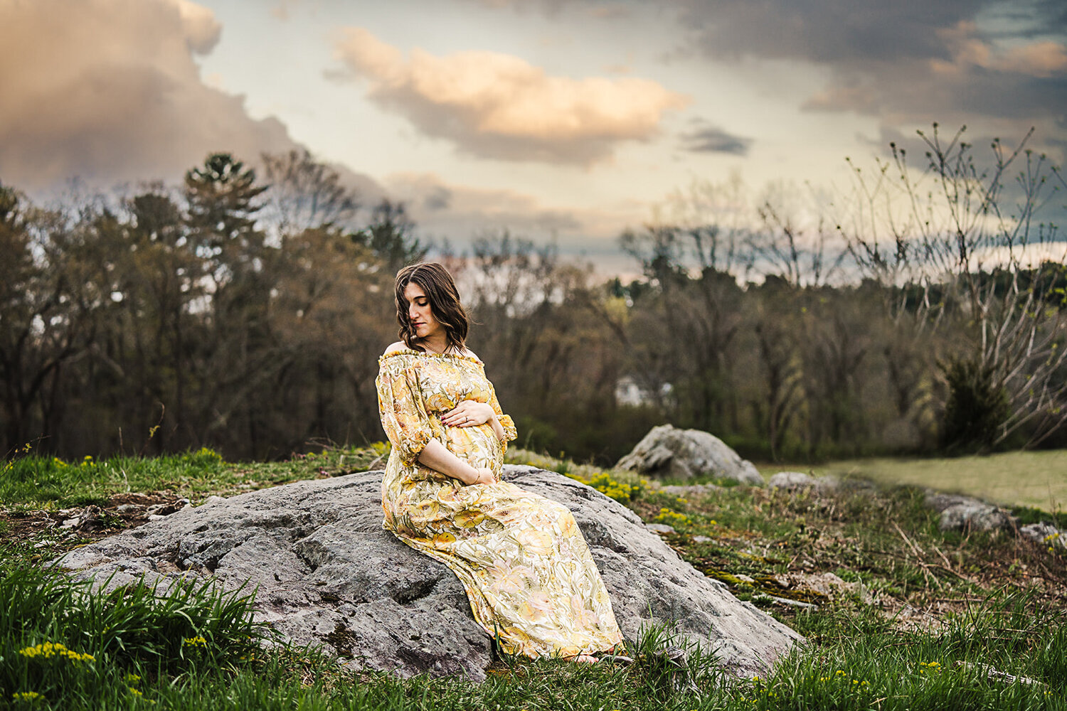 pregnant mom sits on rock for boston maternity photos