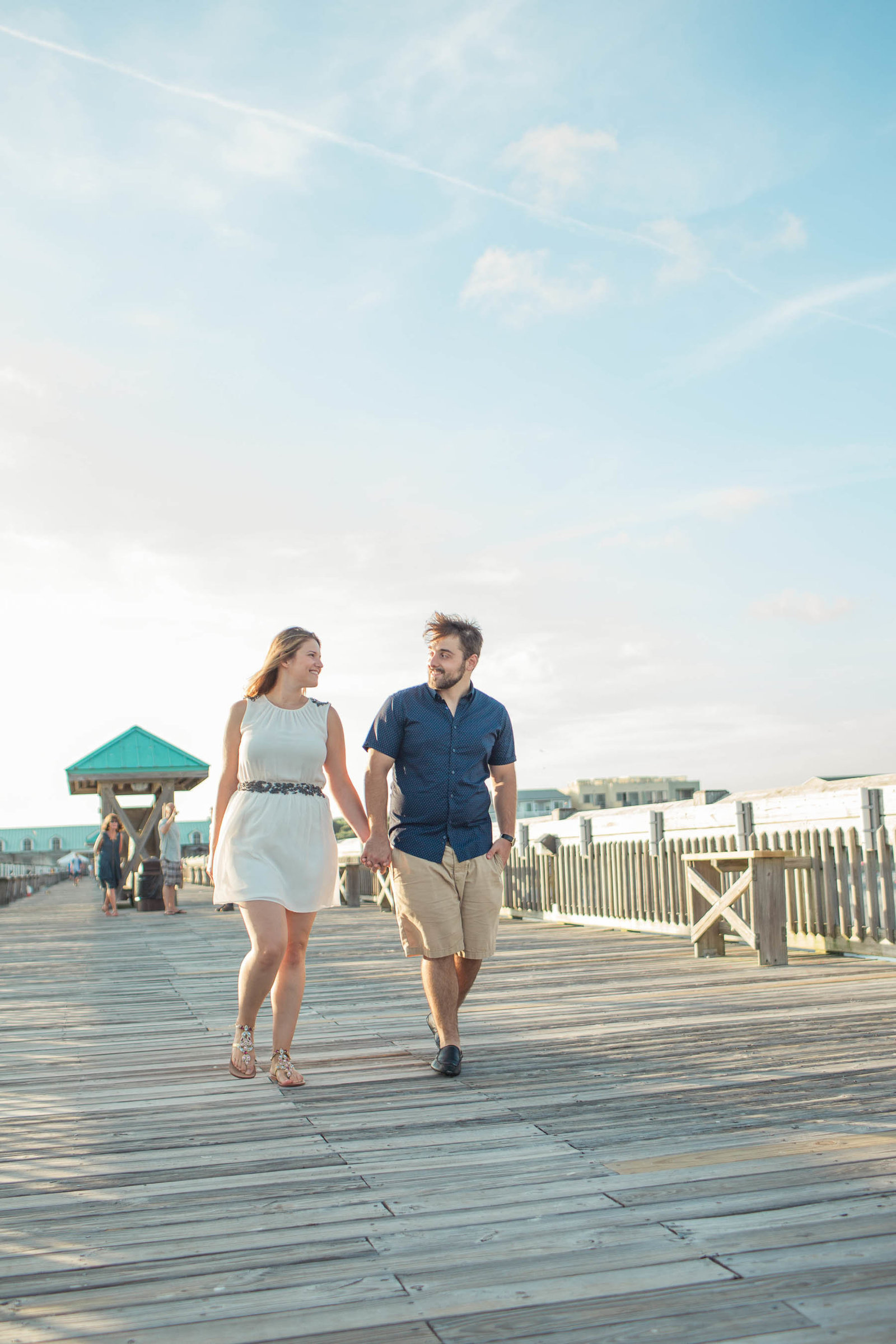 Engaged Couple walk down pier, Folly beach in Charleston, South Carolina
