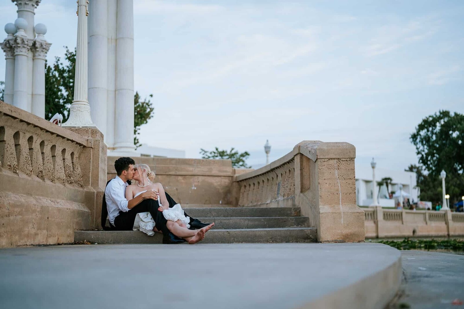 Golden hour couple portraits at Lake Mirror - Magnolia Building Wedding - bride and groom sharing a kiss on the steps at Lake Mirror