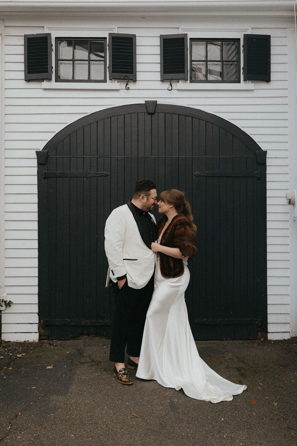 Bride and groom sharing a kiss in front of a black barn door