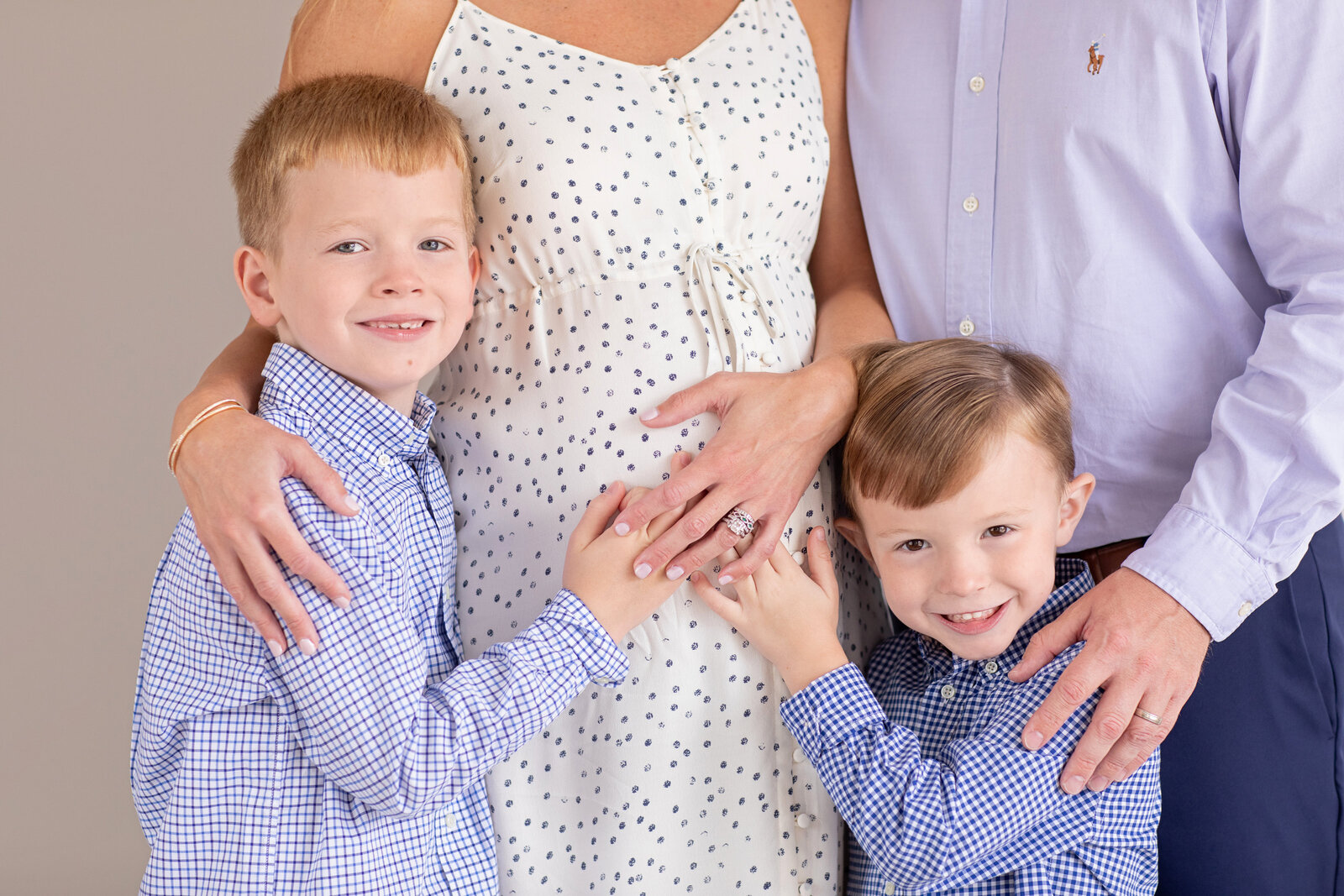 Close-up maternity photo of a pregnant woman’s belly with her two children hugging her sides, captured by Philadelphia maternity photographers.