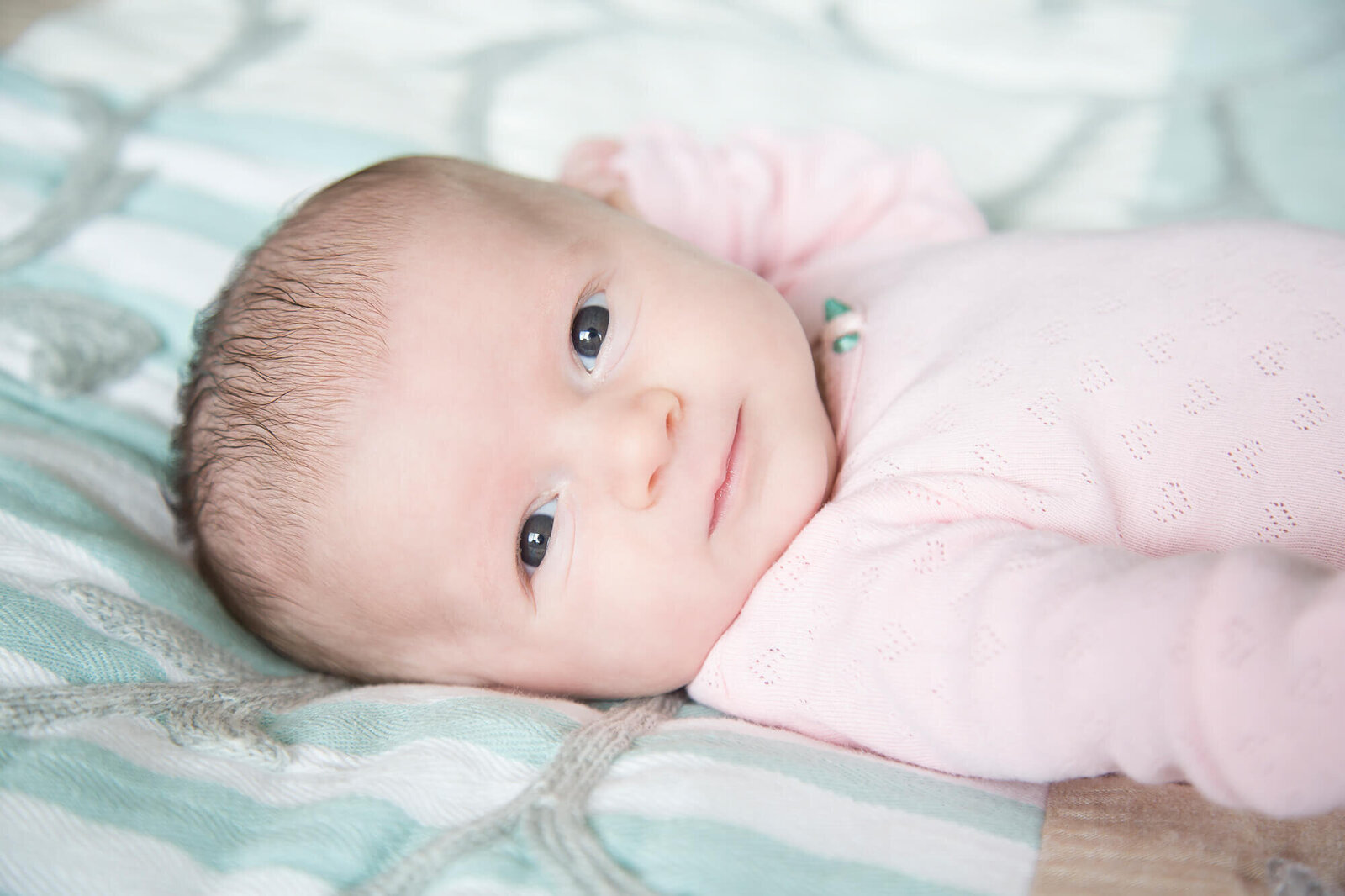 stunning baby girl in pink laying on a bed during session with las vegas milestone photographer Jessica Bowles