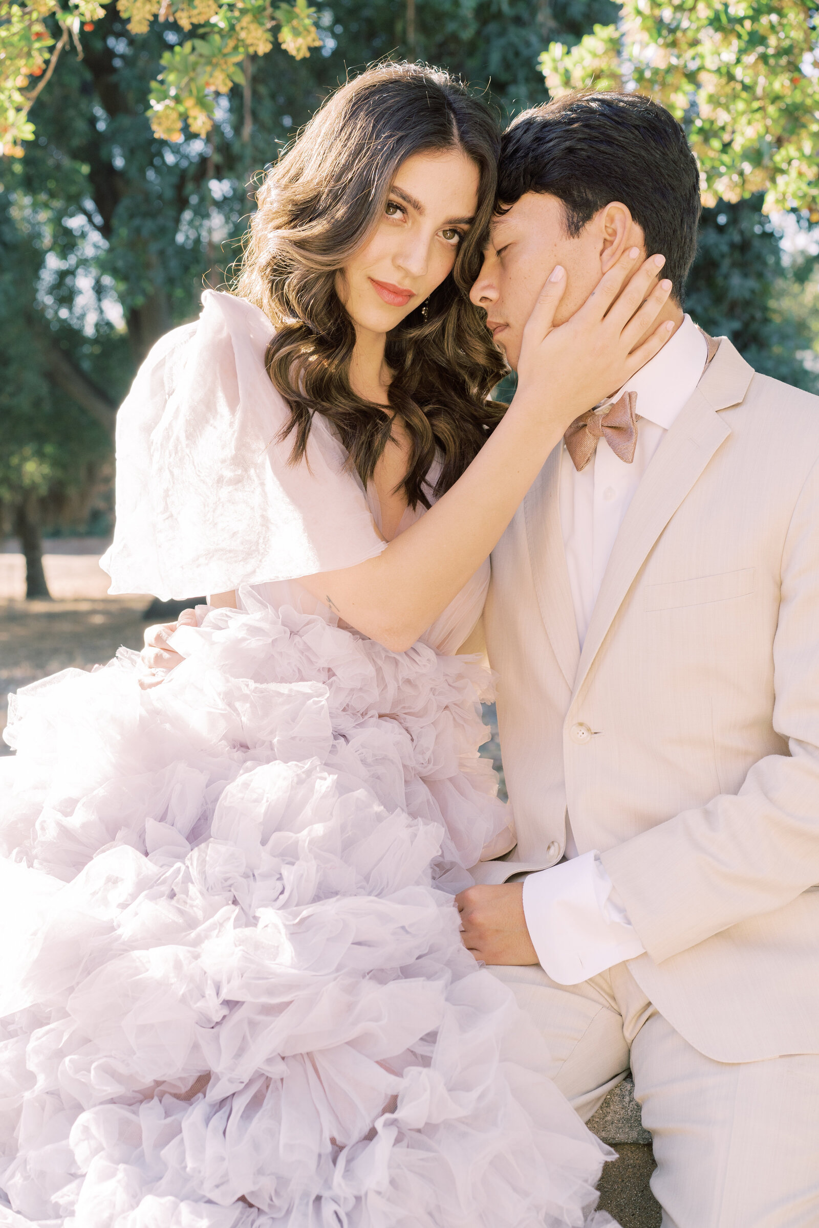 Portrait of bride and groom in a lavender gown and cream suit embracing outdoors.