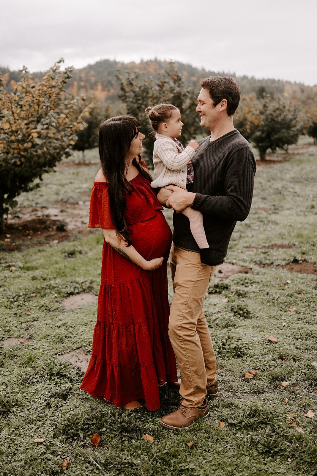 couple holding pregnant belly and toddler