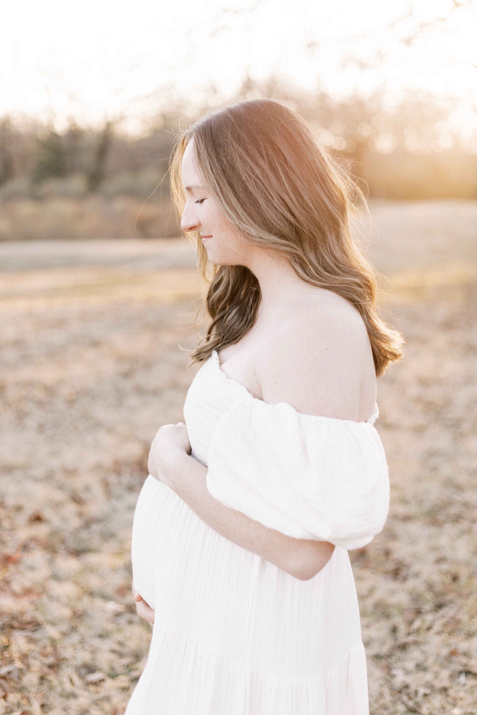 woman looking down and smiling while pregnant in peoria illinois maternity photos 