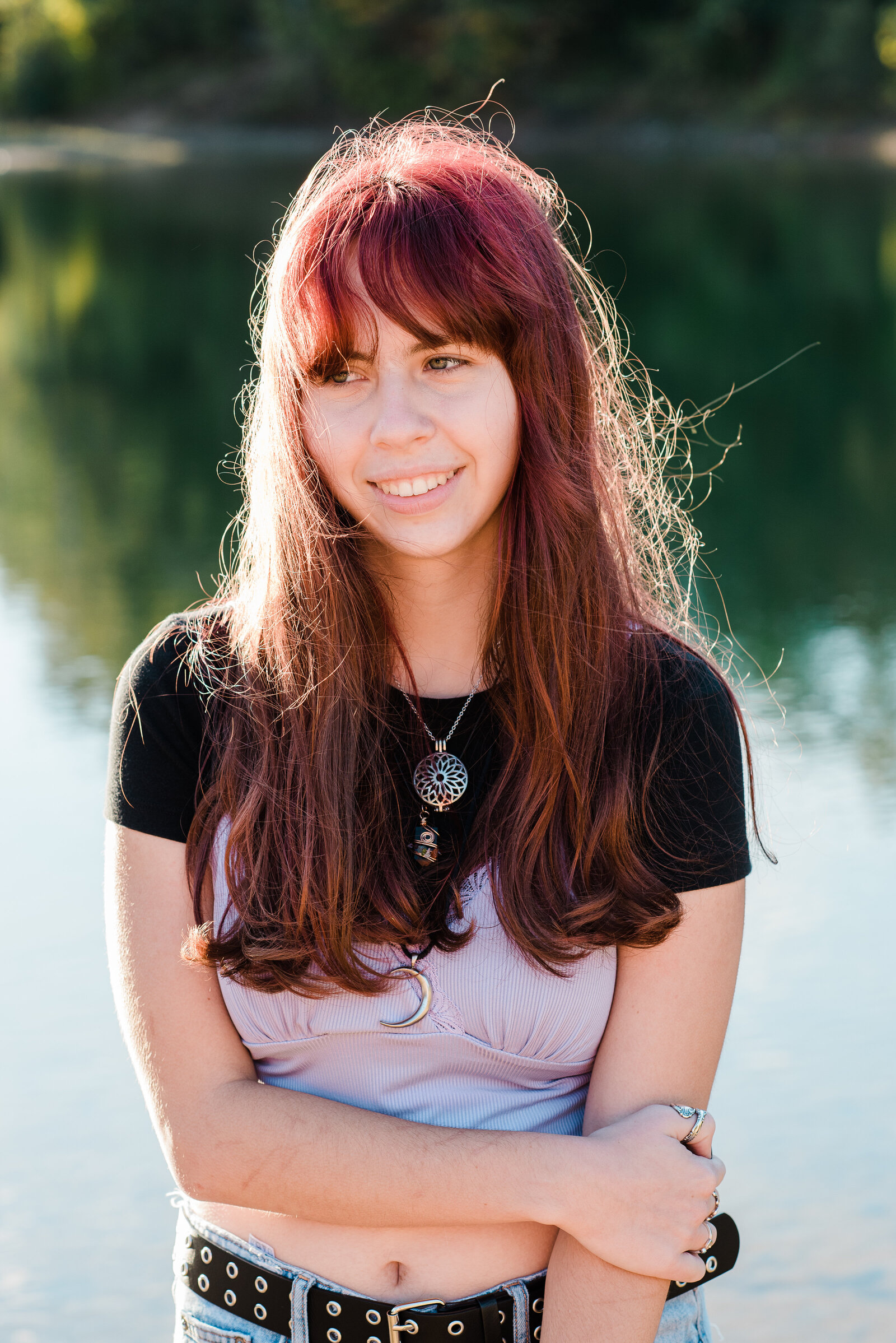 girl holing arm by water in sunlight