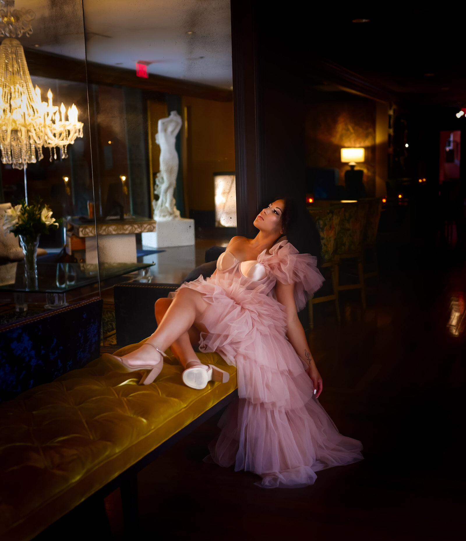 Savannah Boudoir Photography and Glamour showcases gorgeous black woman in pink designer glamour gown in Savannah fancy hotel laying on bench
