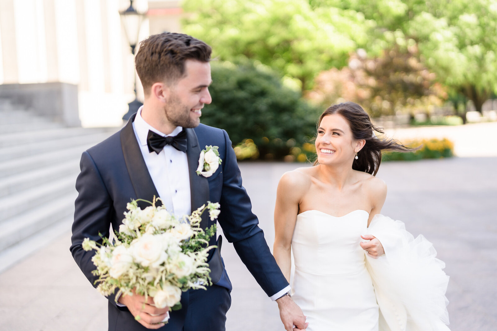 Bride and groom hold hands and run on the grounds of the Ohio Statehouse