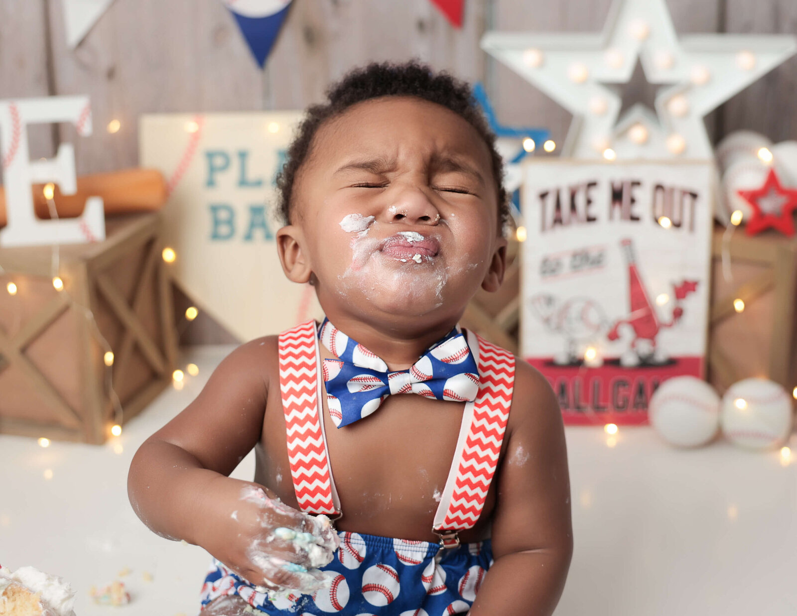A cheerful young boy celebrating his birthday with a baseball-themed cake smash in a studio in Rochester, NY. The scene features colorful decorations, a vibrant baseball cake, and the boy joyfully playing with cake remnants.