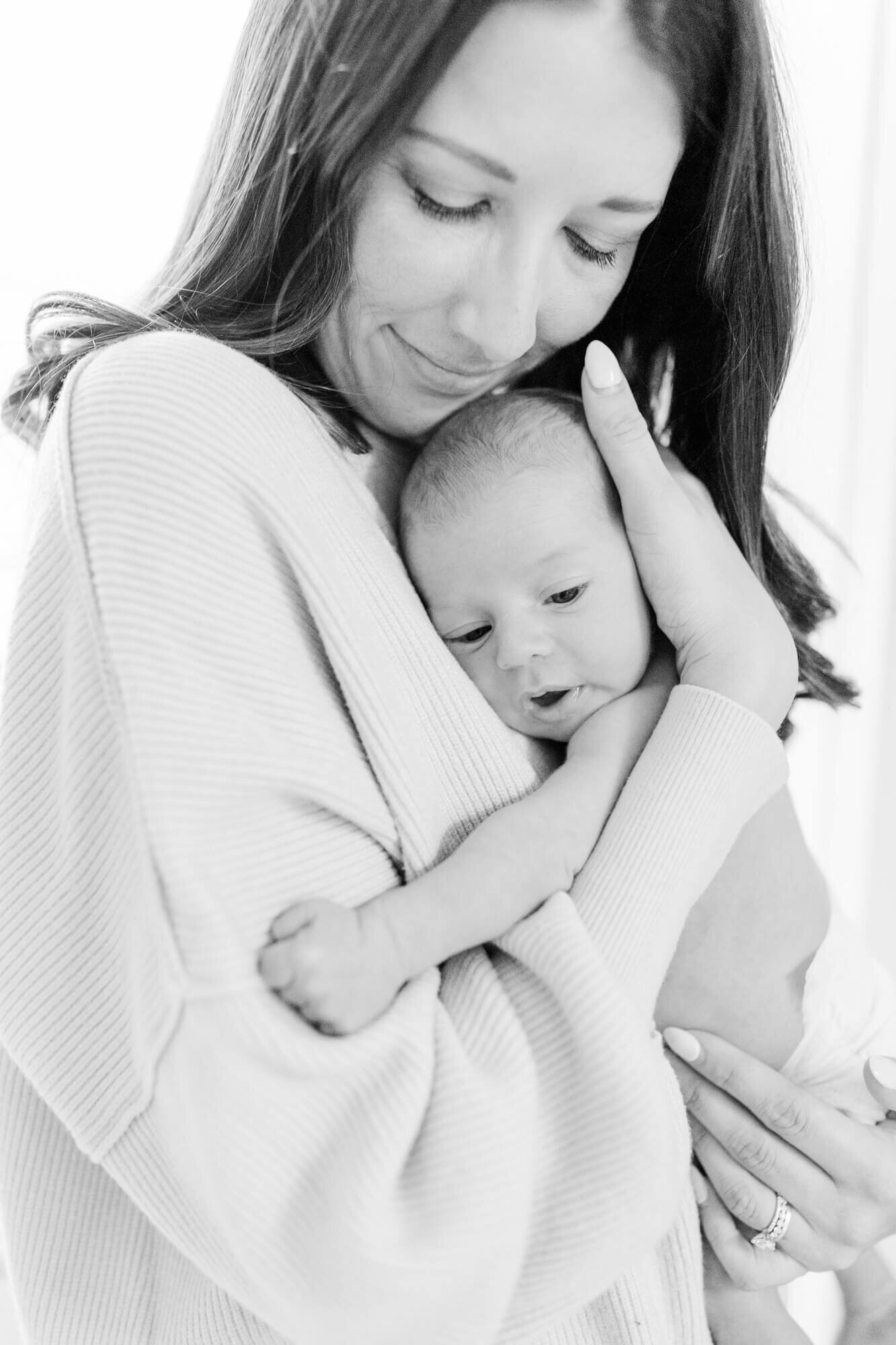 Black and white, mom holds newborn to her chest