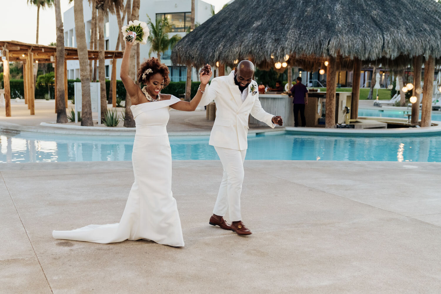 Bride and groom dancing joyfully by a poolside venue