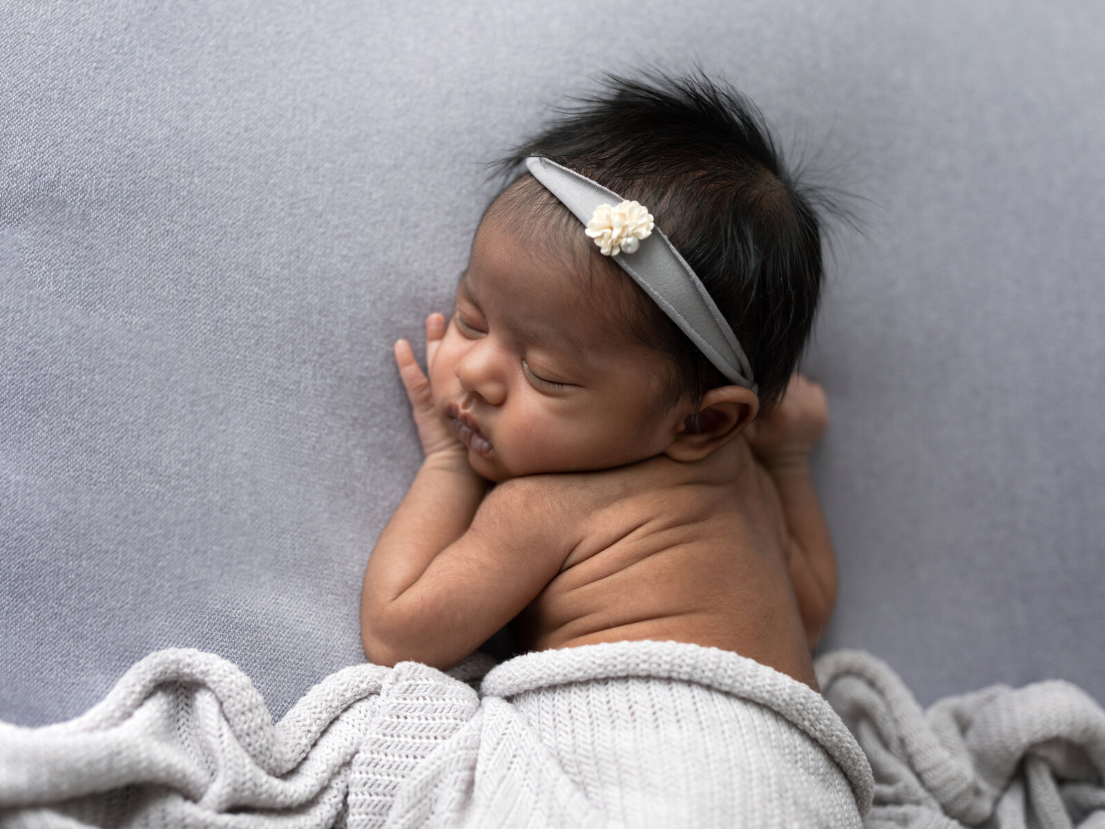 newborn baby girl posed on gray fabric for studio newborn portraits