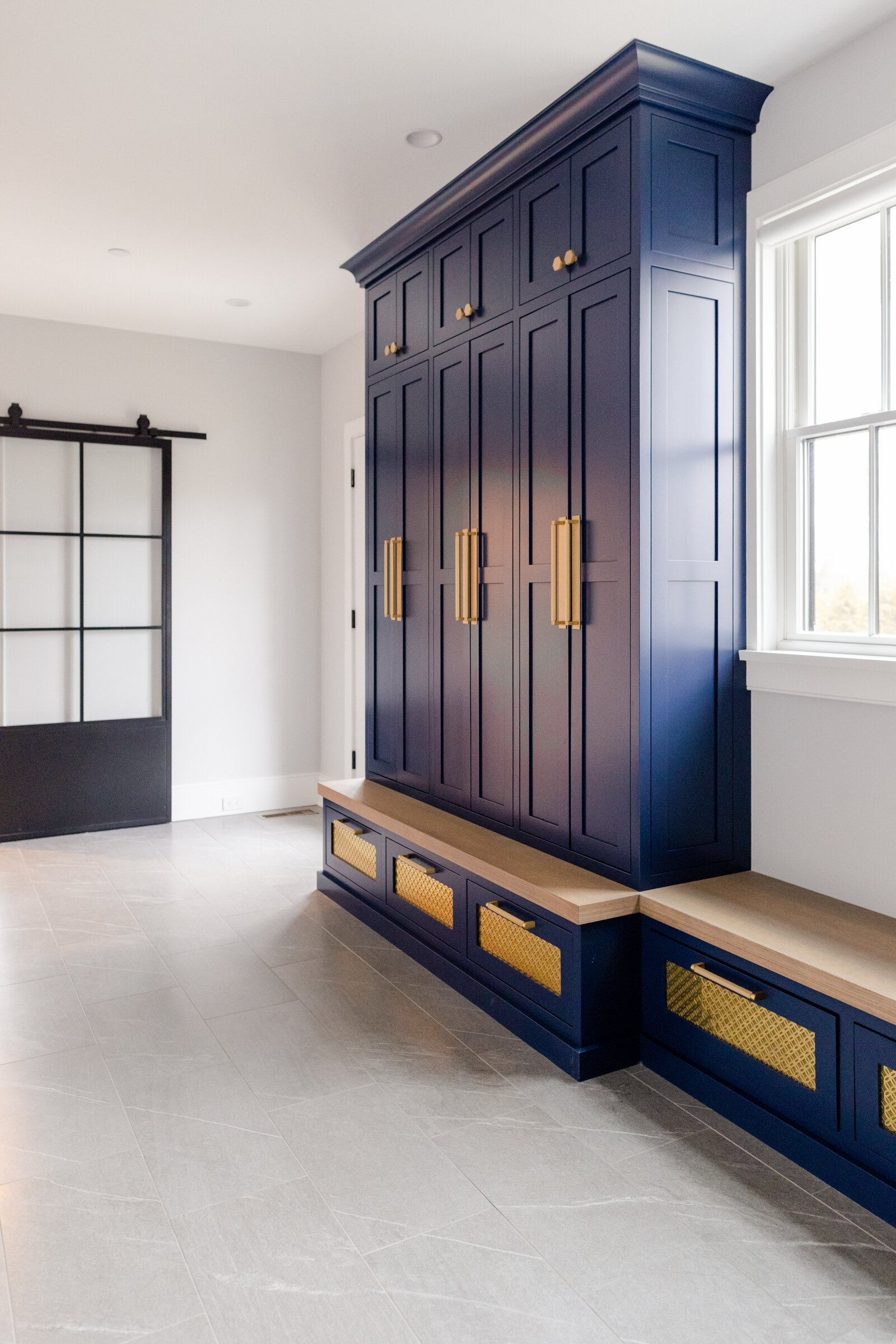 The mudroom includes blue cabinetry with a built-in bench for storage, along with an entryway featuring 12x12 porcelain tiles and navy blue storage cabinets.