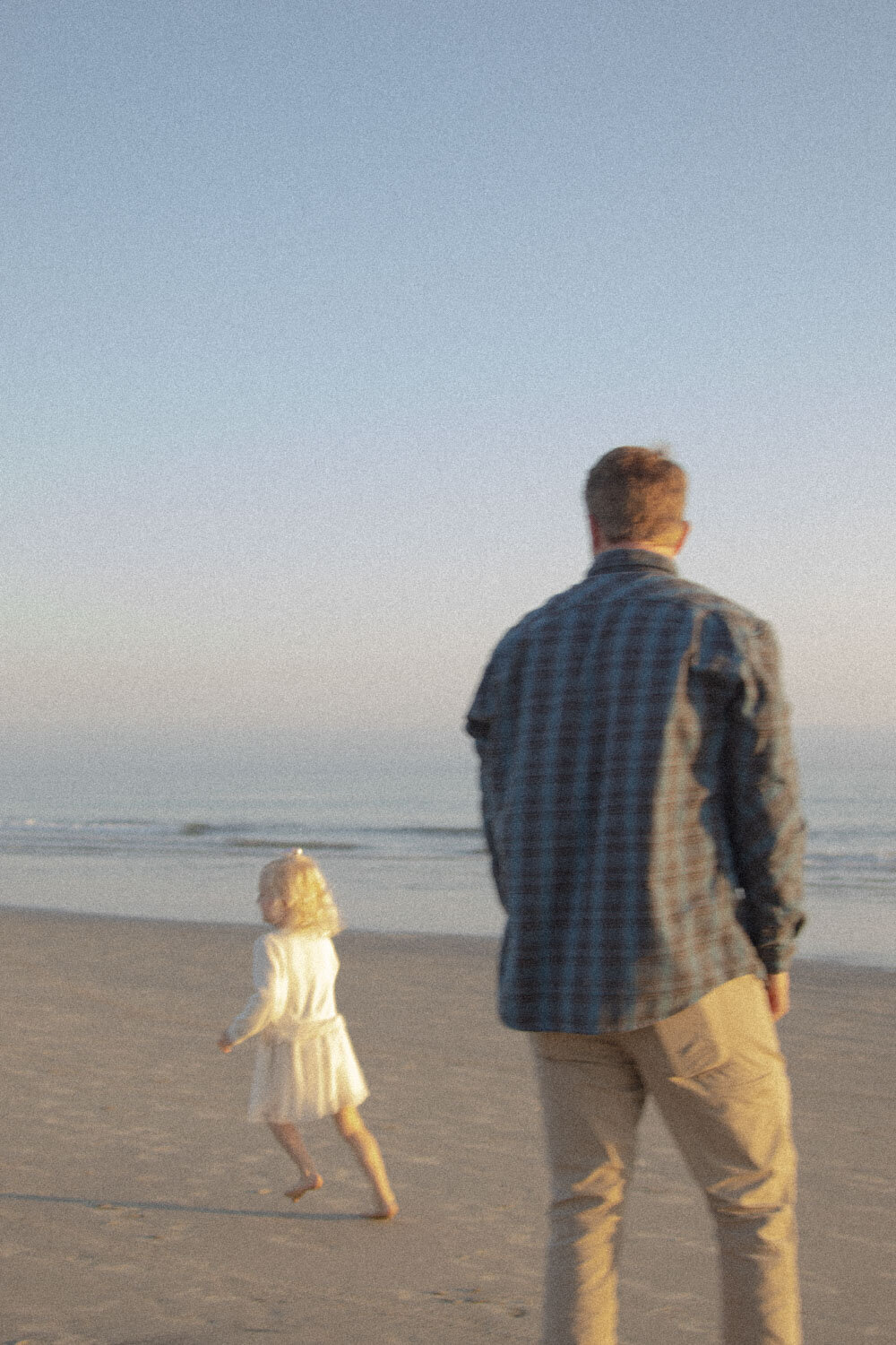 Father walking along the beach with his daughter, captured during a family photography session in San Diego