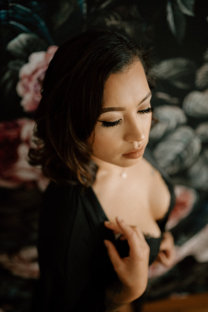 woman in black lingerie in front of floral wall in tacoma boudoir studio