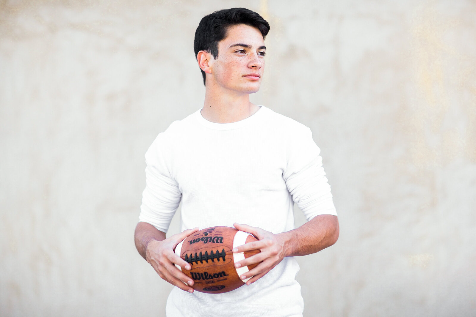 high school senior boy posing with football