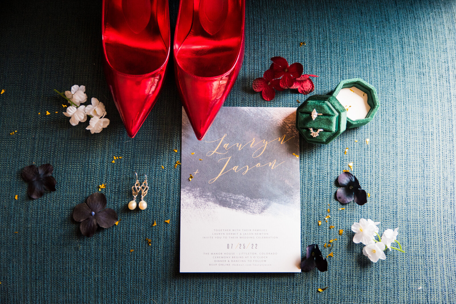 The wedding details including an invitation, jewelry, and bright red heels.