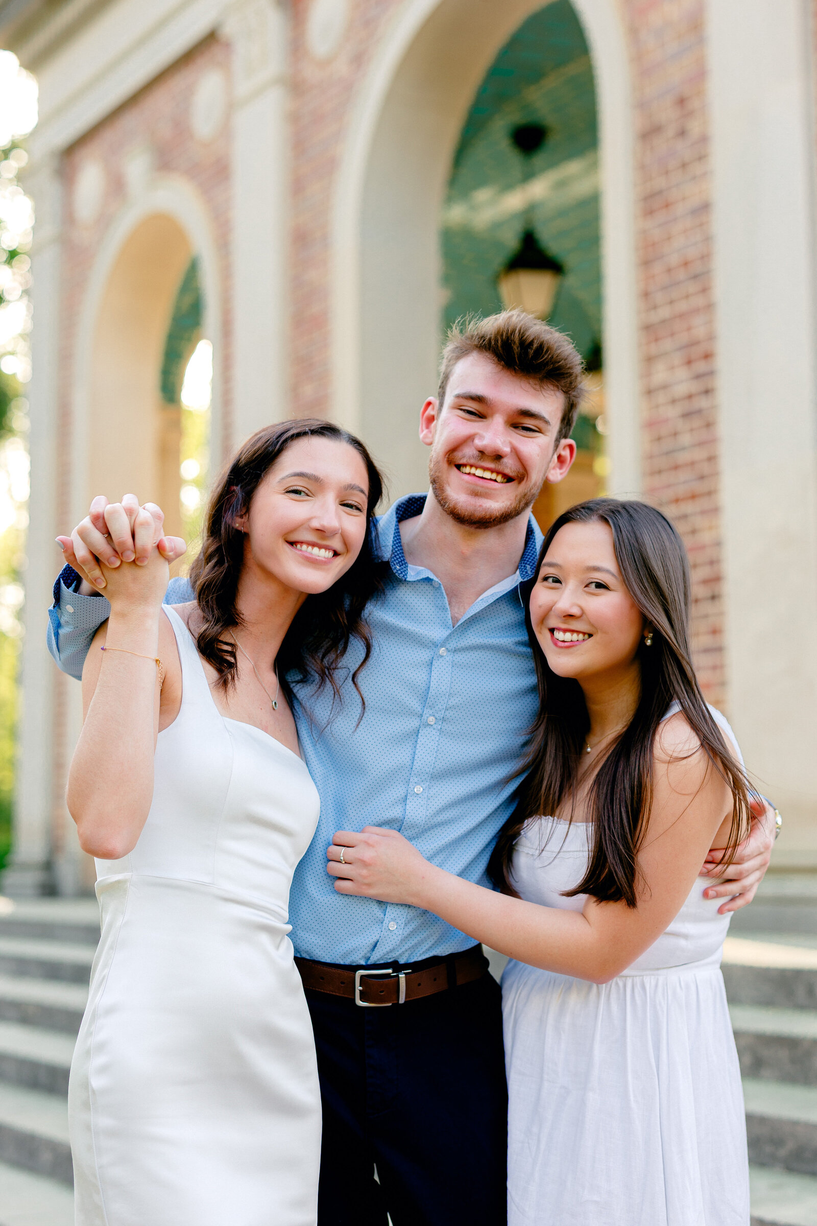 Group of UNC graduates smiling and posing together for portraits at the Bell Tower in Chapel Hill.