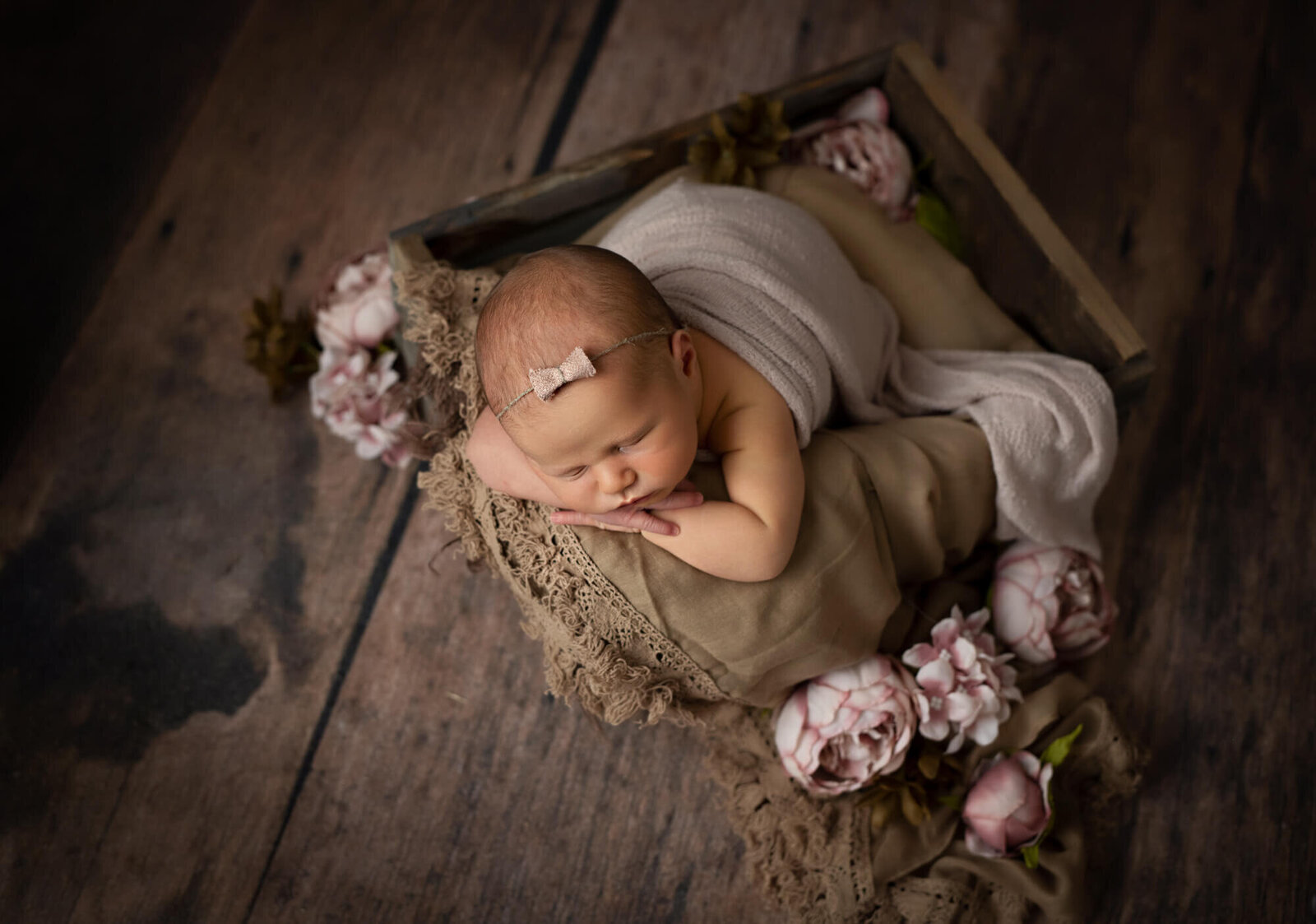 sleeping baby girl in brown crate with pink flowers