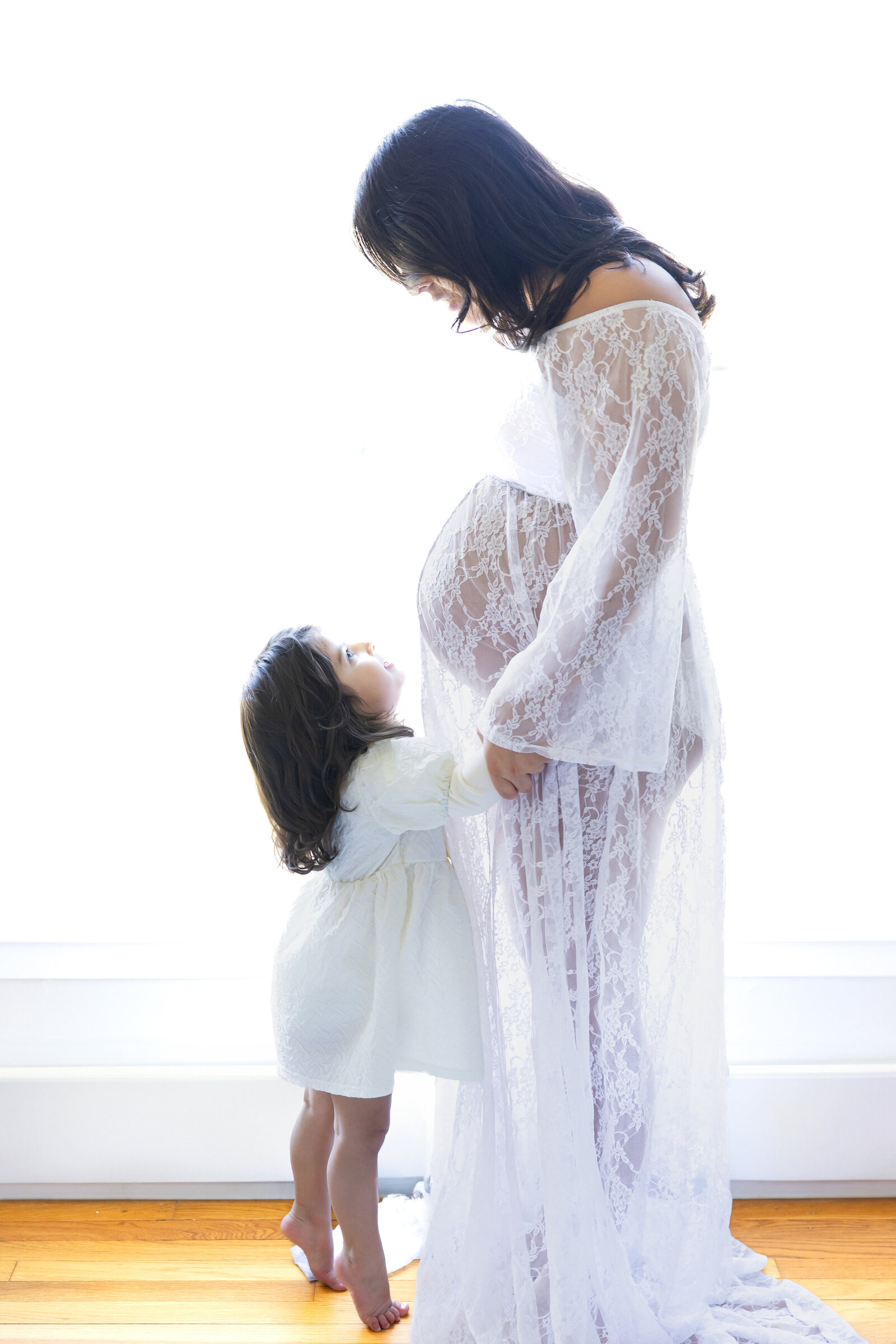 Lifestyle maternity portrait of a daughter hugging her mother.