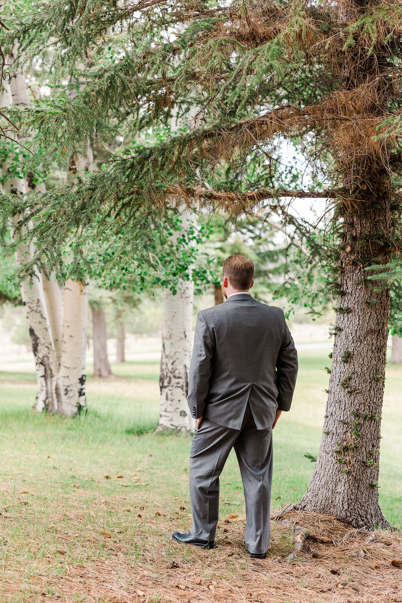 Groom standing with his back turned, waiting to see his bride for the first look at a Ridgway State Park wedding