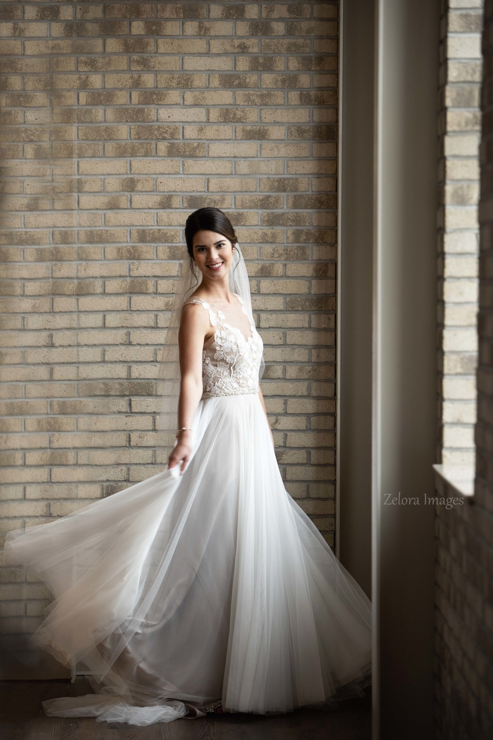 Bride by window in front of a brick wall