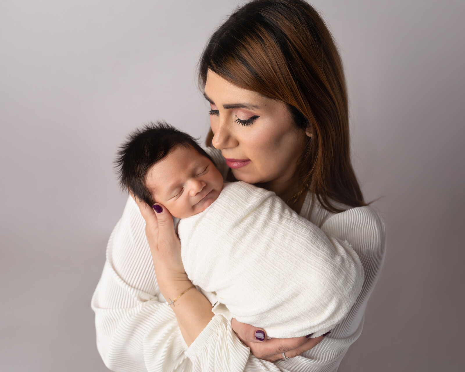 Mom holding newborn baby boy for studio portraits