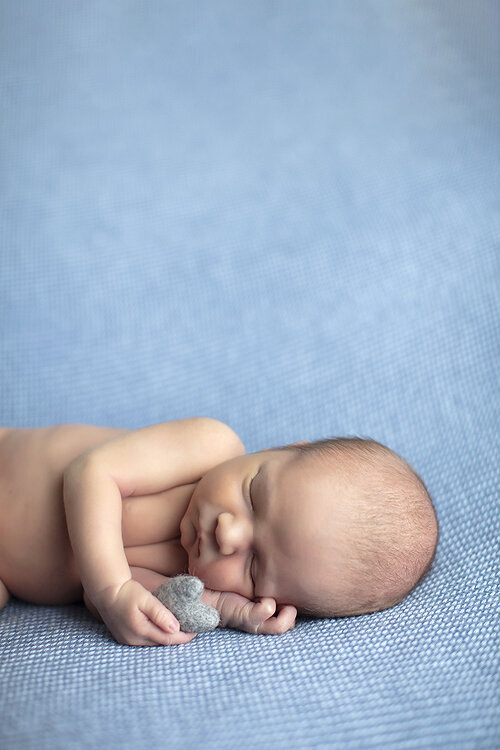 Newborn holding heart,  a Dallas newborn photographer.