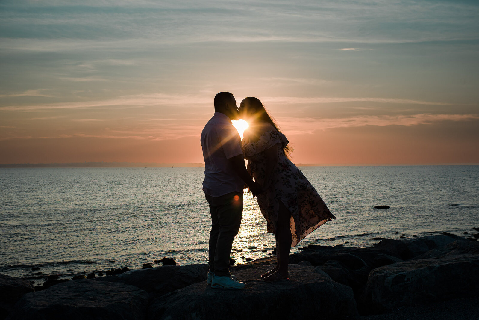 silhouette of couple by water in sunset with pink sky