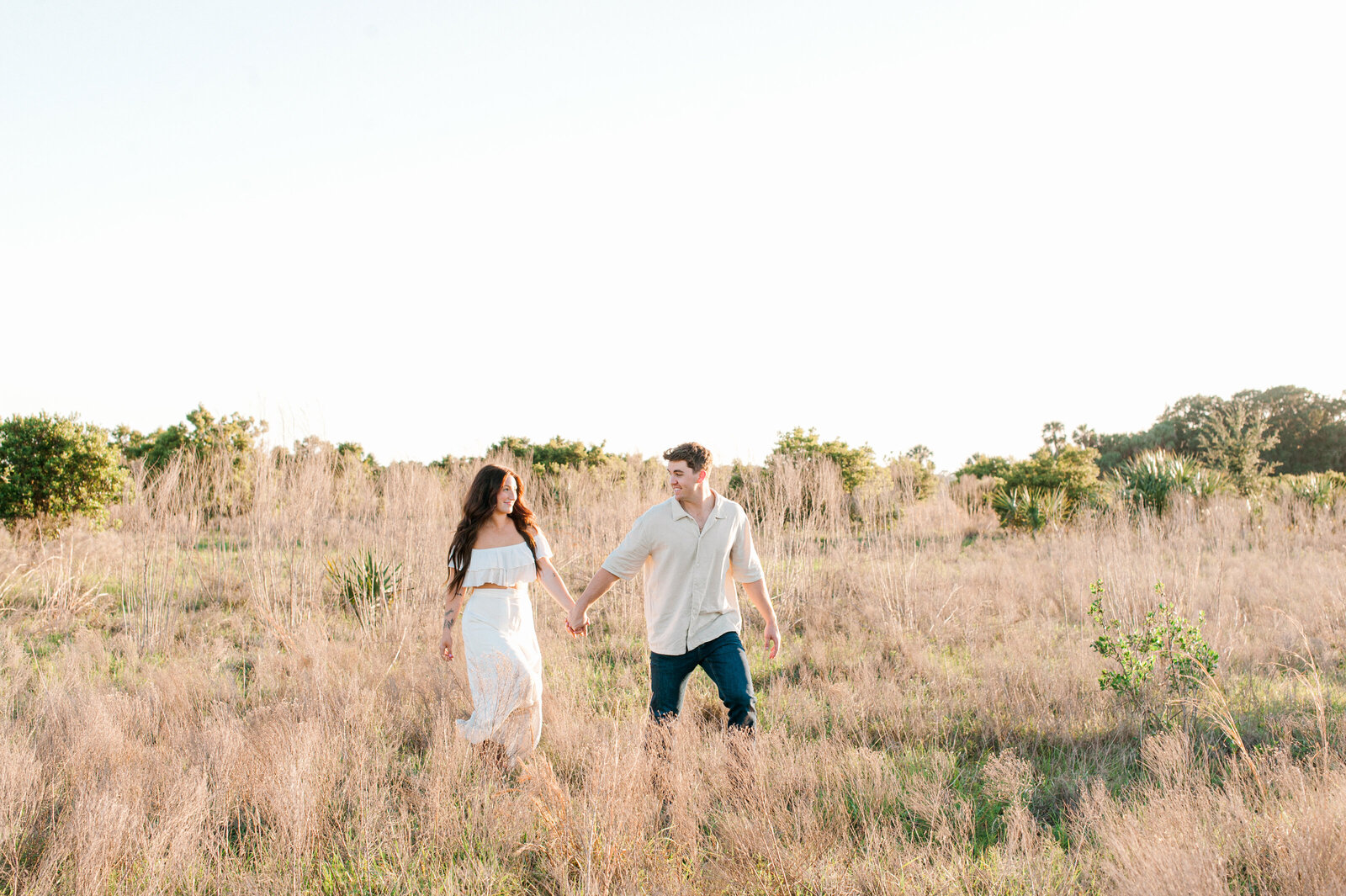 Photographer captures couple walking in a tall grass field  in Orlando