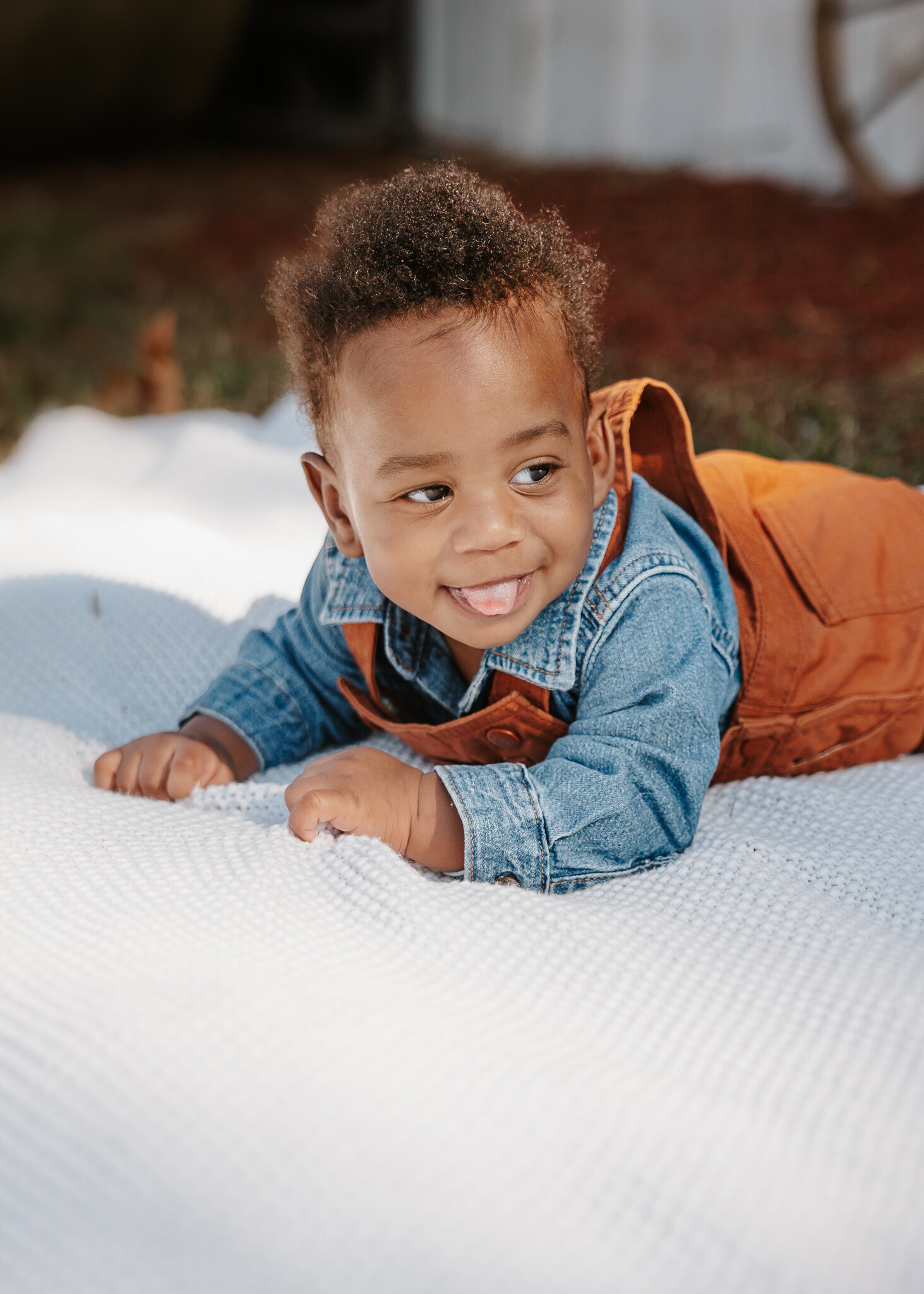 Baby boy smiling while laying on a blanket during his 6-month milestone photoshoot in Hephzibah GA at Tripp Ranch.