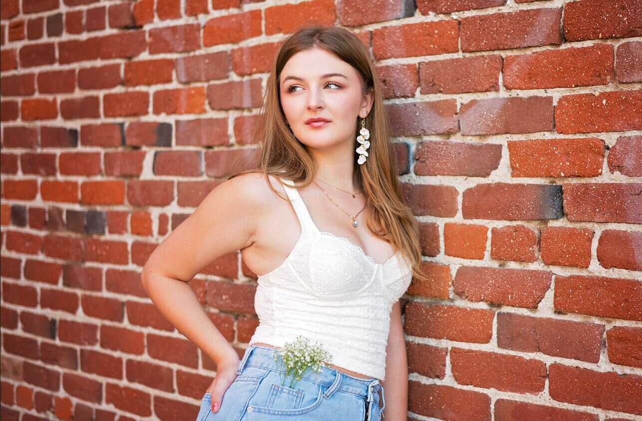High School Senior leaning up against a brick wall. 