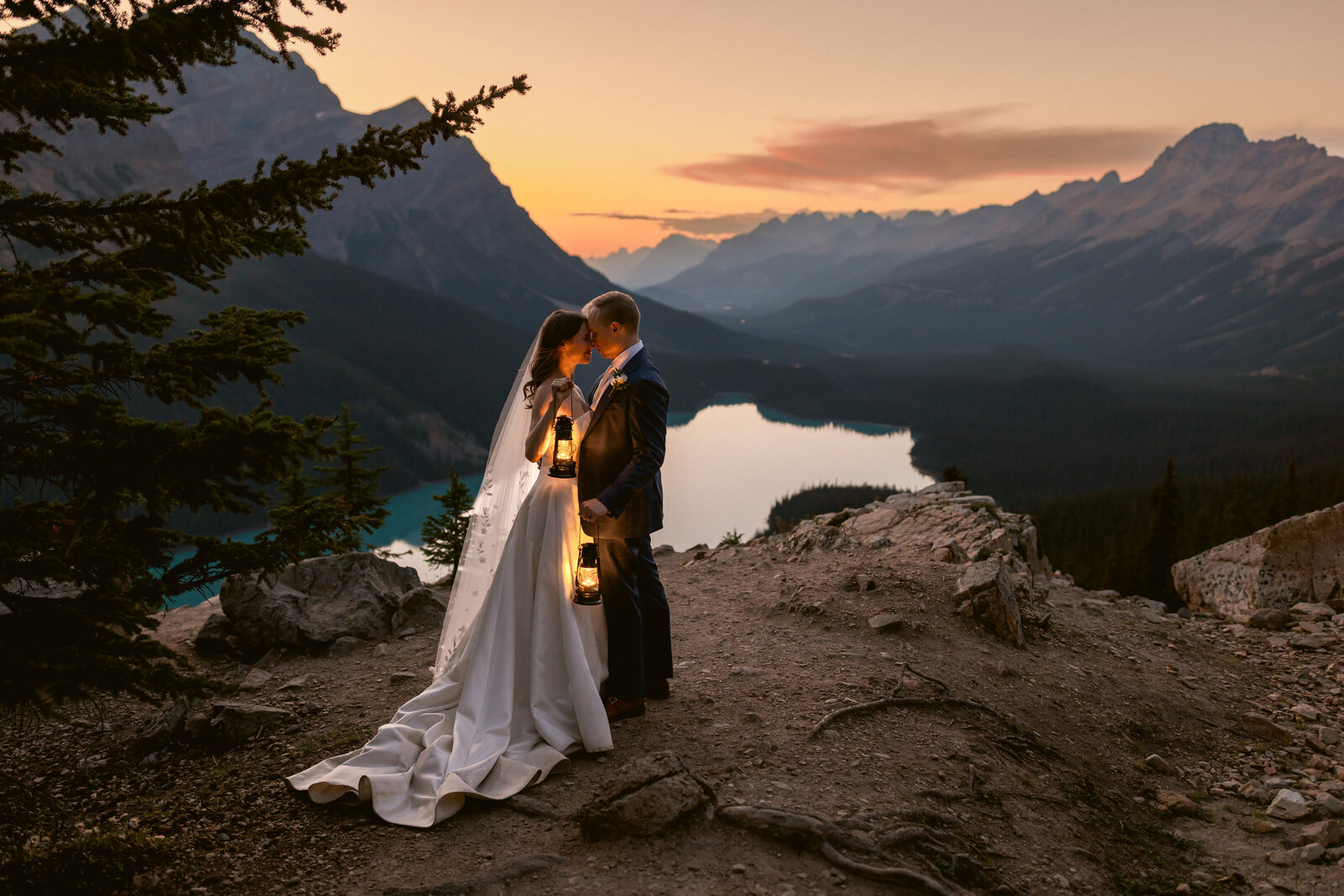 A breathtaking moment as a couple stands atop a mountain in Banff National Park, the bride’s dress flowing in the wind on a warm summer day. Arriving by private helicopter for their intimate ceremony, this dramatic photograph by the Canadian Rockies best elopement photographer captures the essence of adventure, love, and epic romance in the Canadian Rockies.