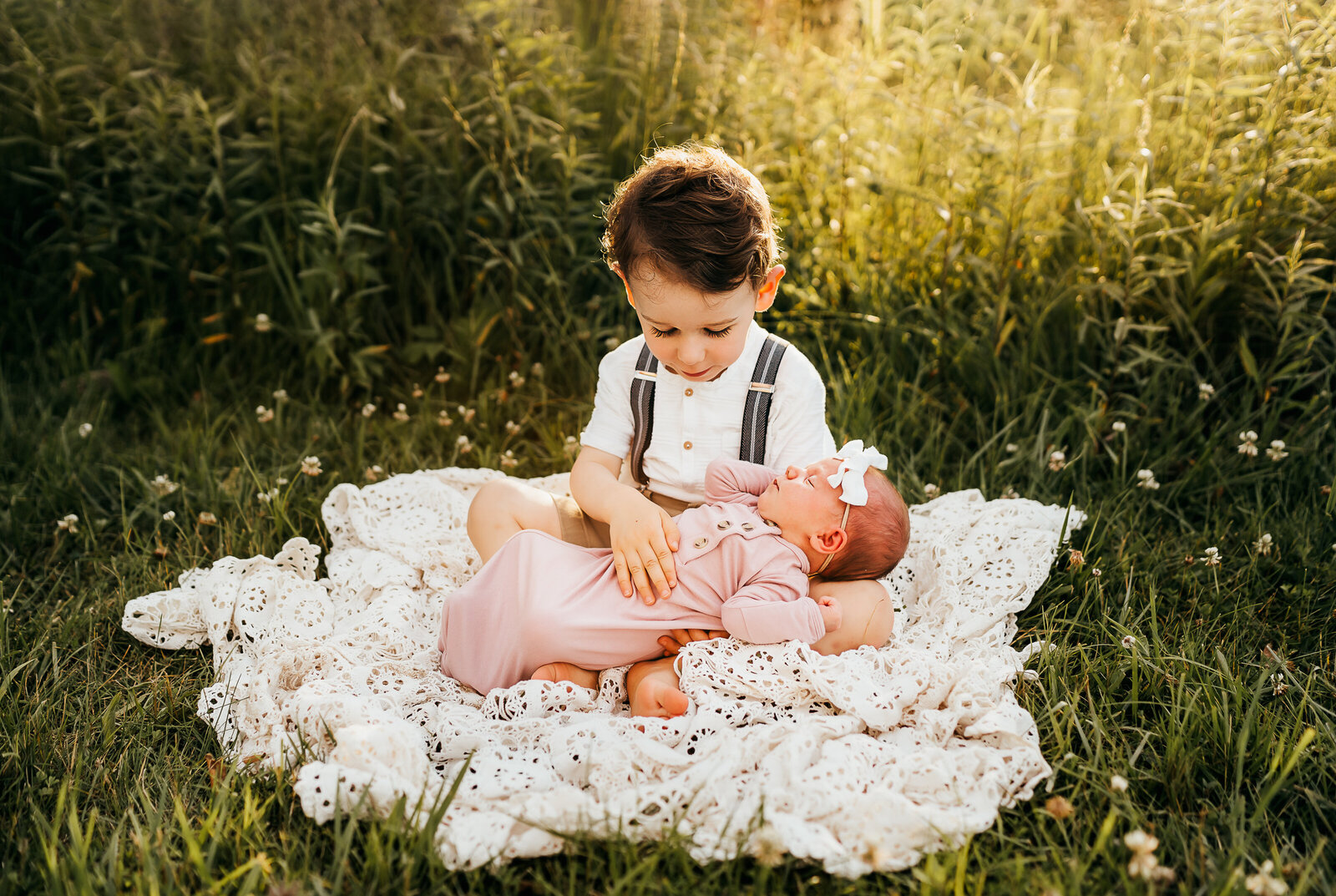 boy holding baby sister in field