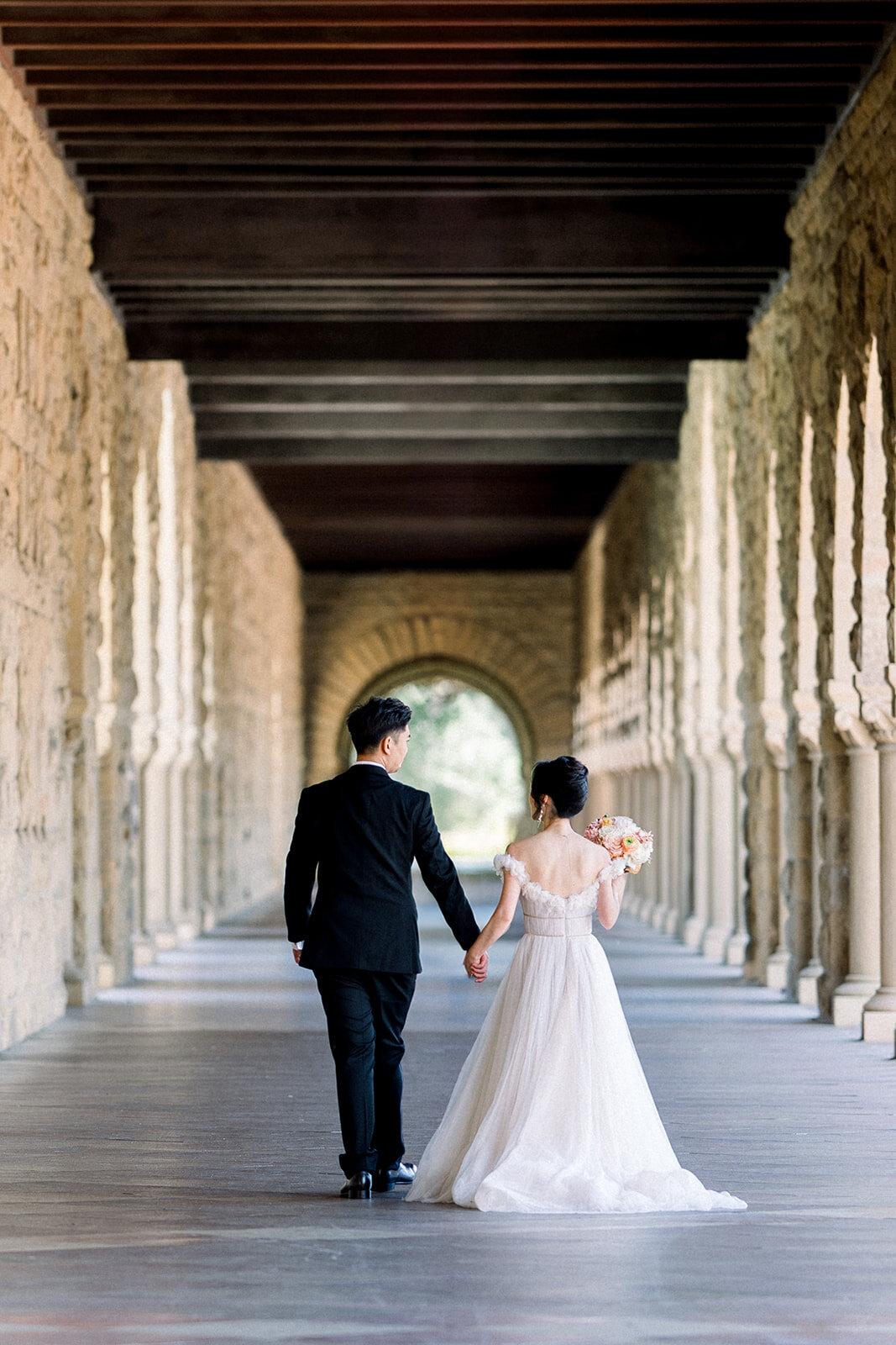 The bride and groom share a romantic dance under the iconic arches of Stanford University, highlighting their love and connection.