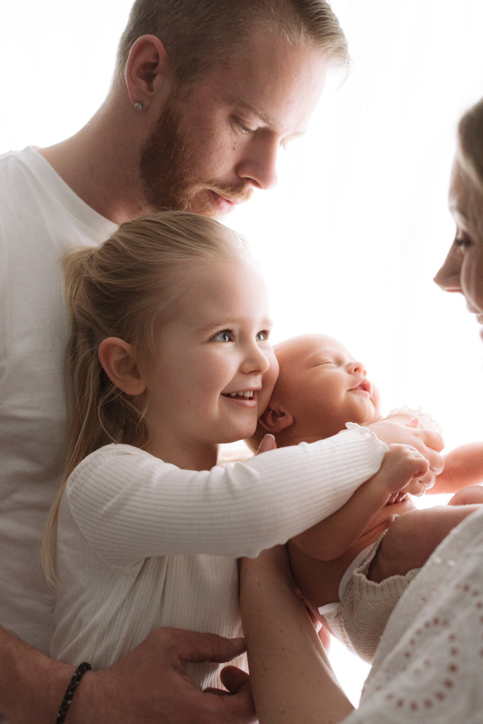 Little girl hugging her baby brother and  smiling on newborn photoshoot in west sussexLittle girl hugging her baby brother and  smiling on newborn photoshoot in Billingshurst
