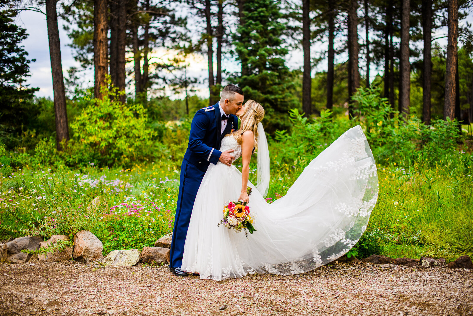 Bride and Groom kissing with flowers pine trees at the Arboretum at Flagstaff
