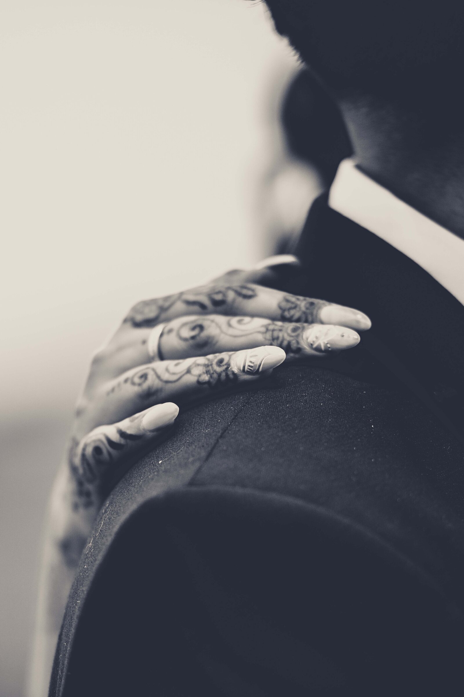 This stunning photograph showcases the intricate henna designs on the bride's hand as it gently rests on her husband's shoulder, symbolizing their newly formed bond. The fine details of the henna reflect the meticulous preparation and cultural significance of their union. Ideal for couples who appreciate the beauty of traditional wedding elements and those looking for inspiration for their own multicultural celebrations.