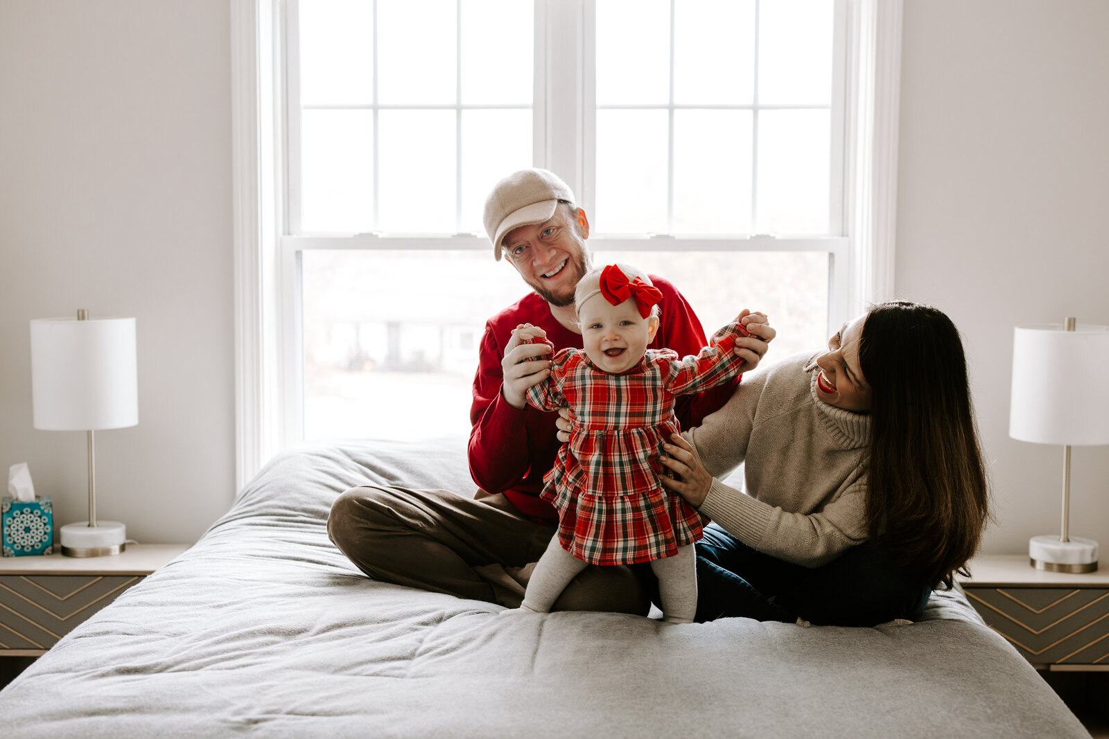 Baby and her parents smile during their in-home  family photo session in Londonderry, New Hampshire