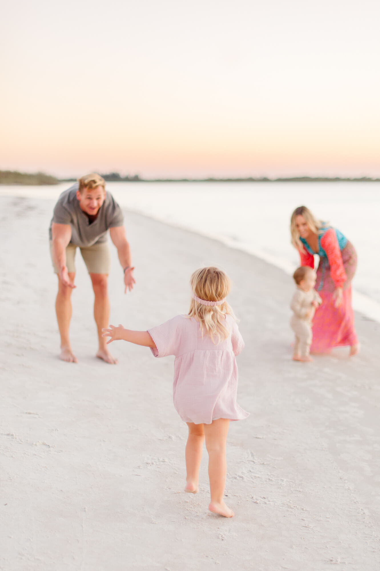 Family of four running and playing on the beach near the shoreline